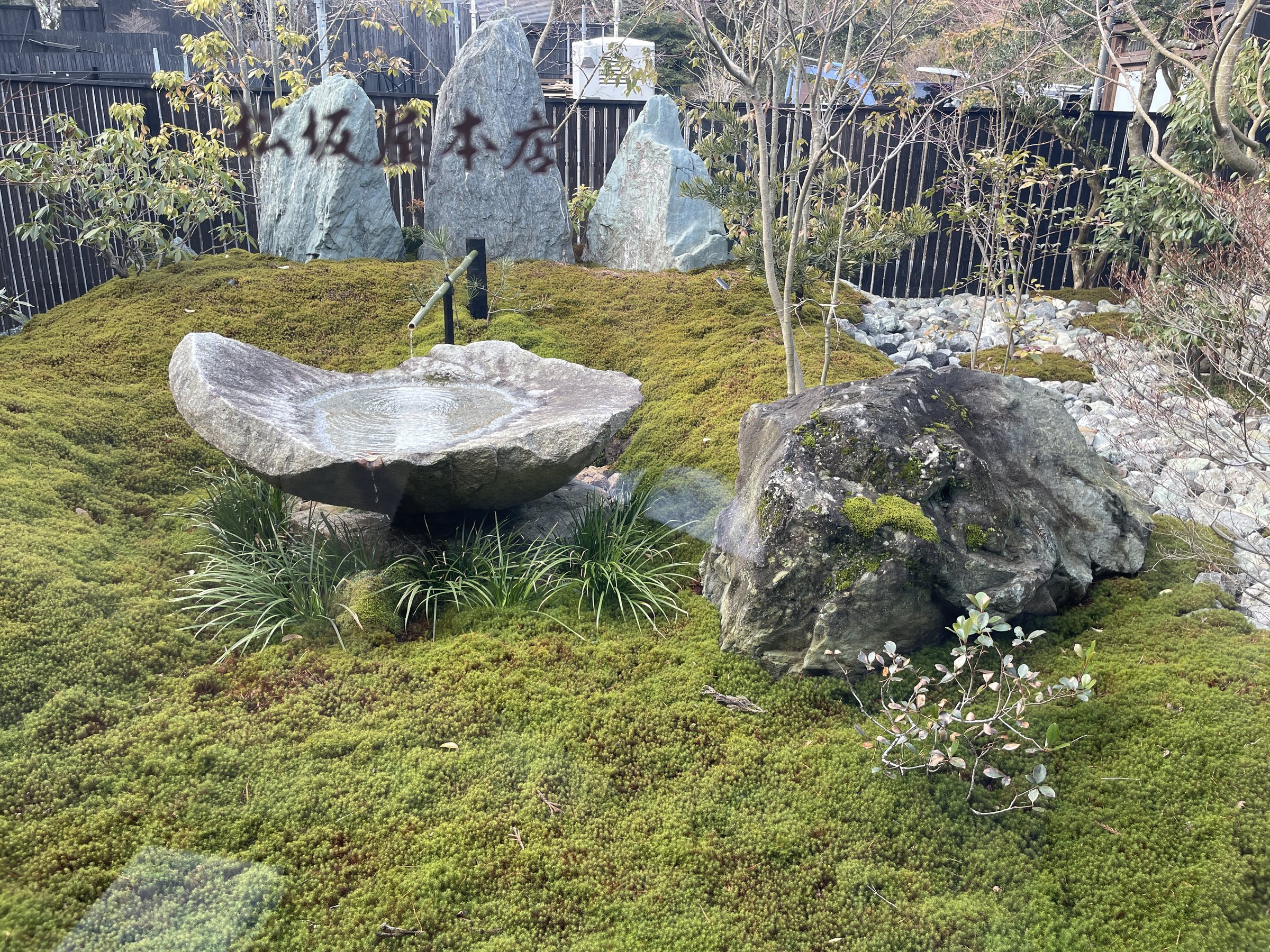 A moss garden with standing stones carved with the ryokan's name.