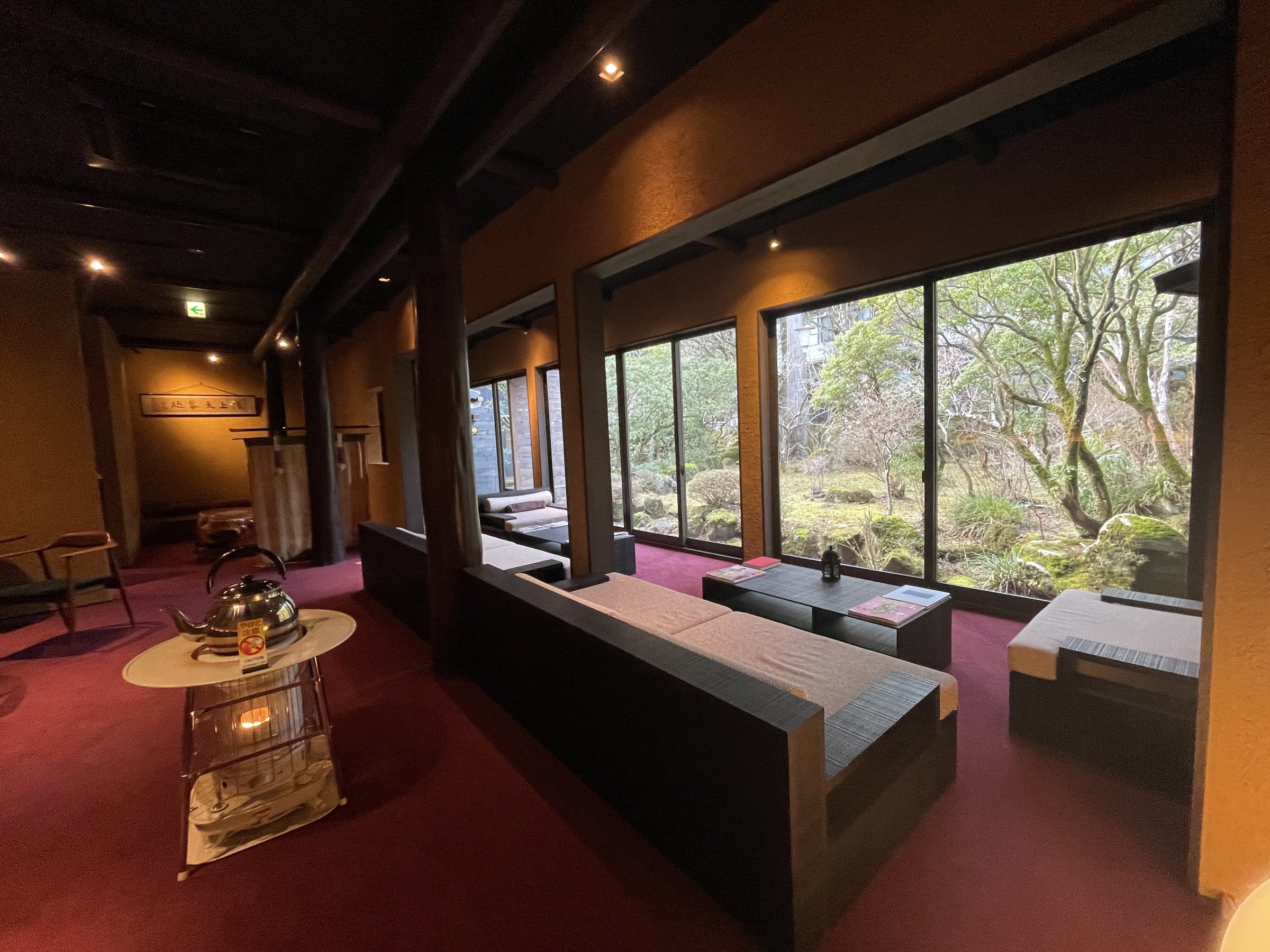 The lounge, with long sofas facing tall windows on to the garden and a kettle set out on a stand.