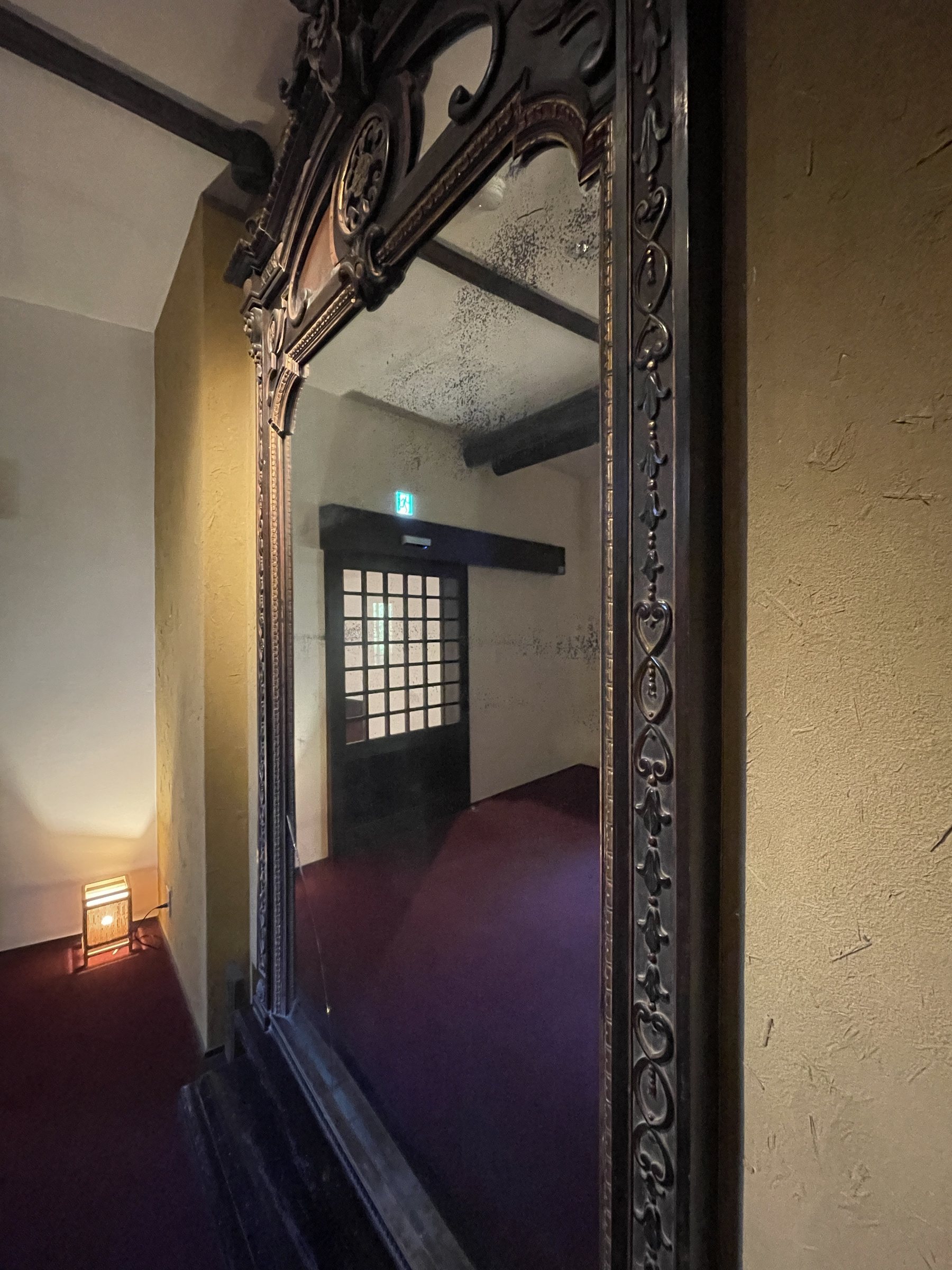 The imperial mirror in its carved dark frame, in a dimly lit corner.