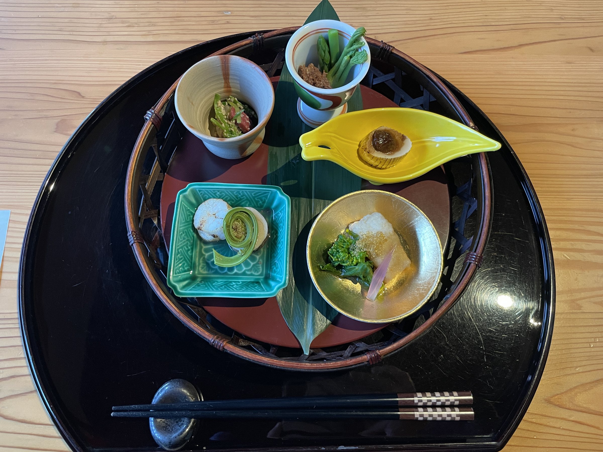 The sakizuke: small dishes of spring vegetables arranged on a black lacquered tray.