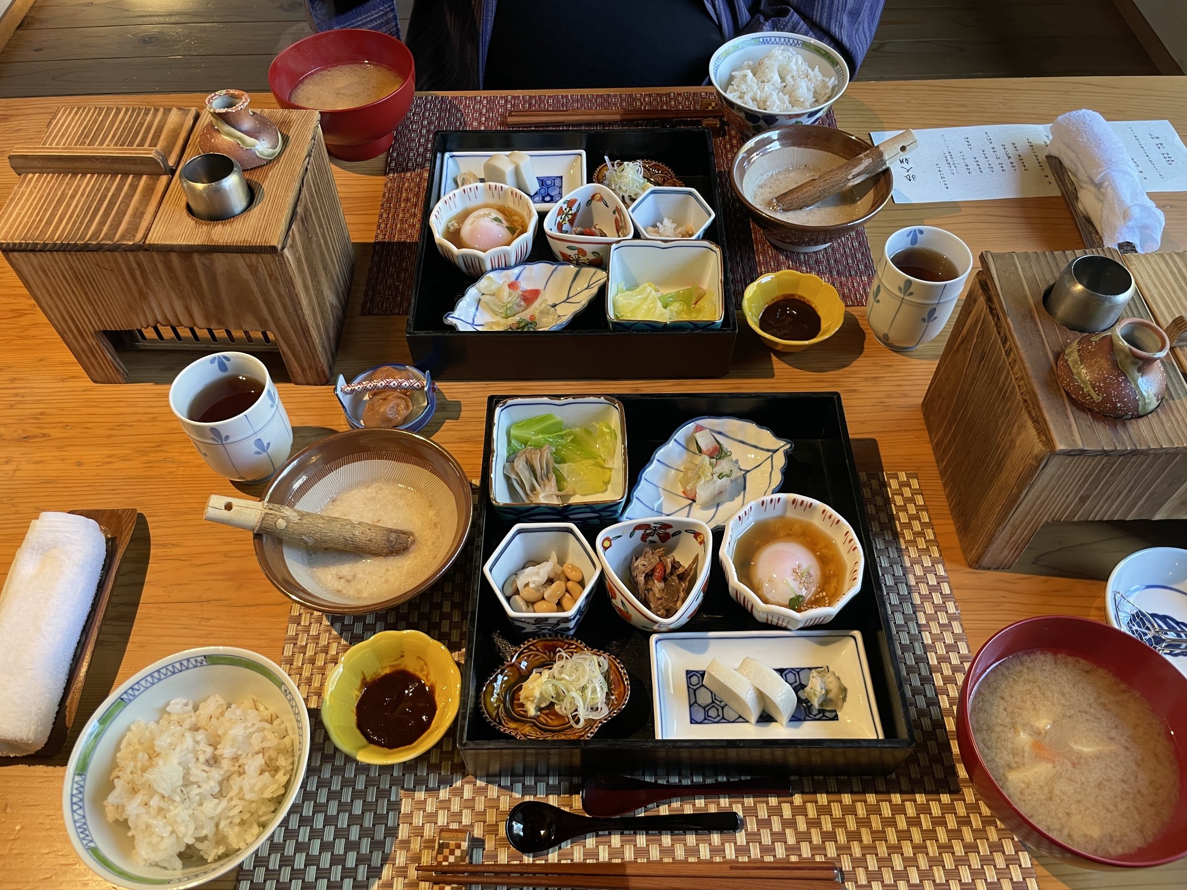Breakfast for two: small dishes in lacquered boxes, barley rice, grated yam and a wooden box for heating tofu.