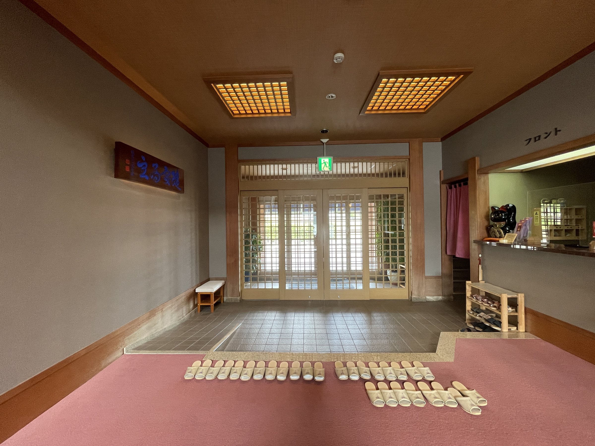 The entrance hall, with slippers lined up on the step and the front desk to one side.