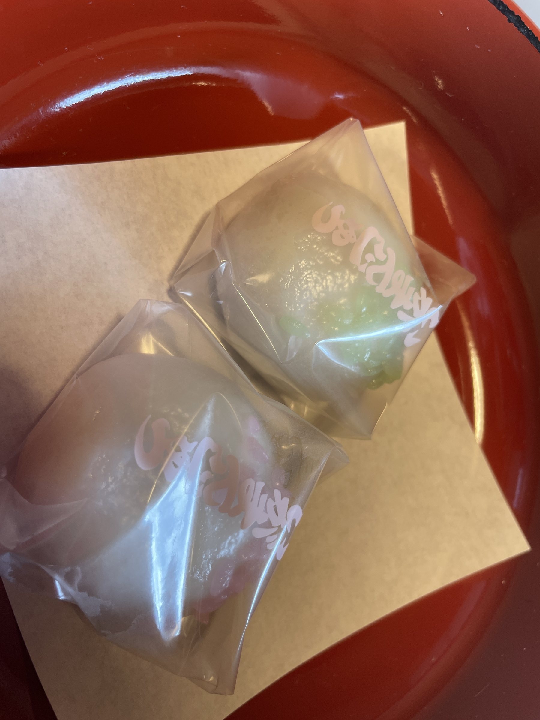 Pale welcome sweets in their wrappers on a red lacquered tray.