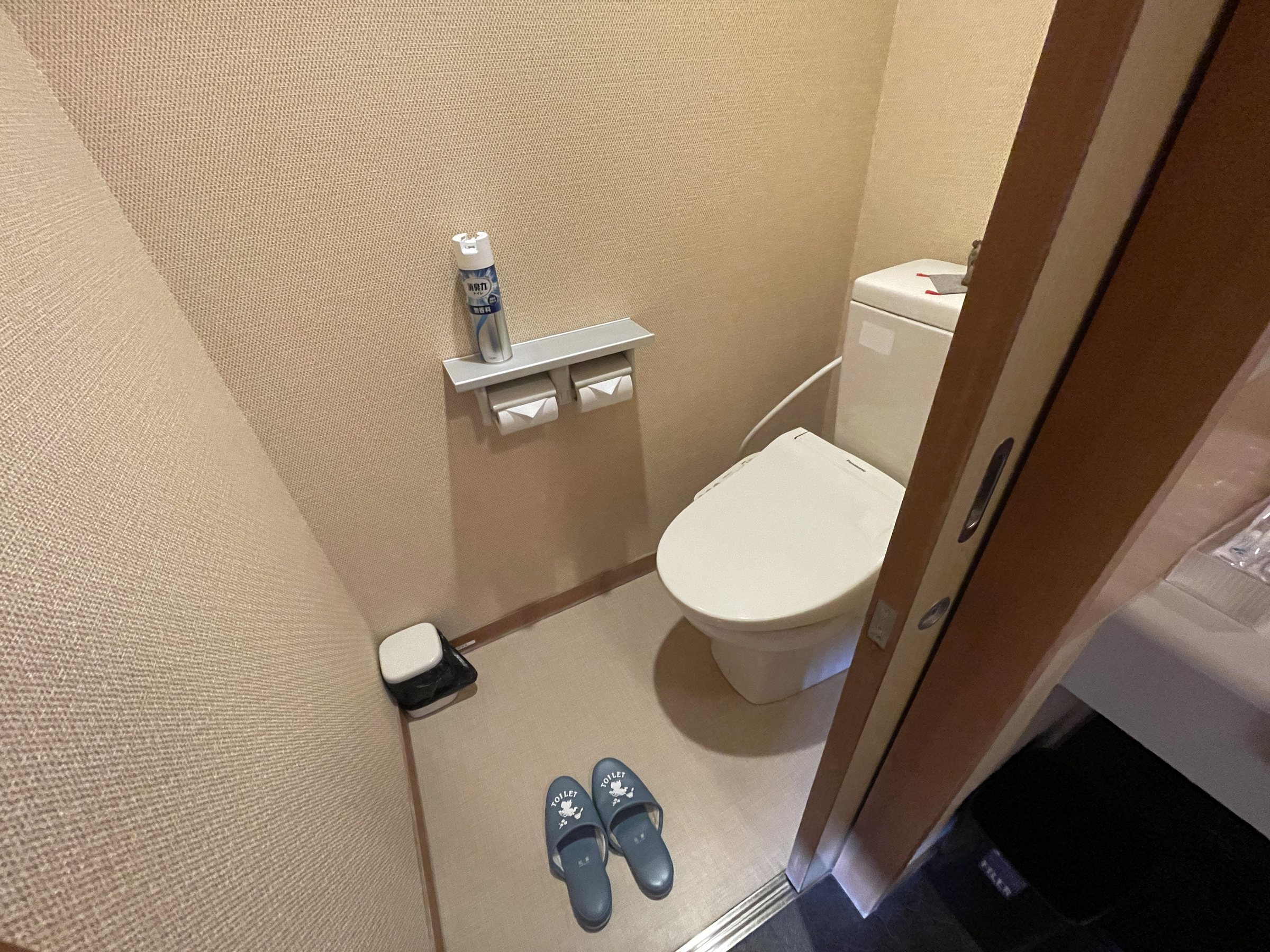 The toilet, with slippers set out at the door.
