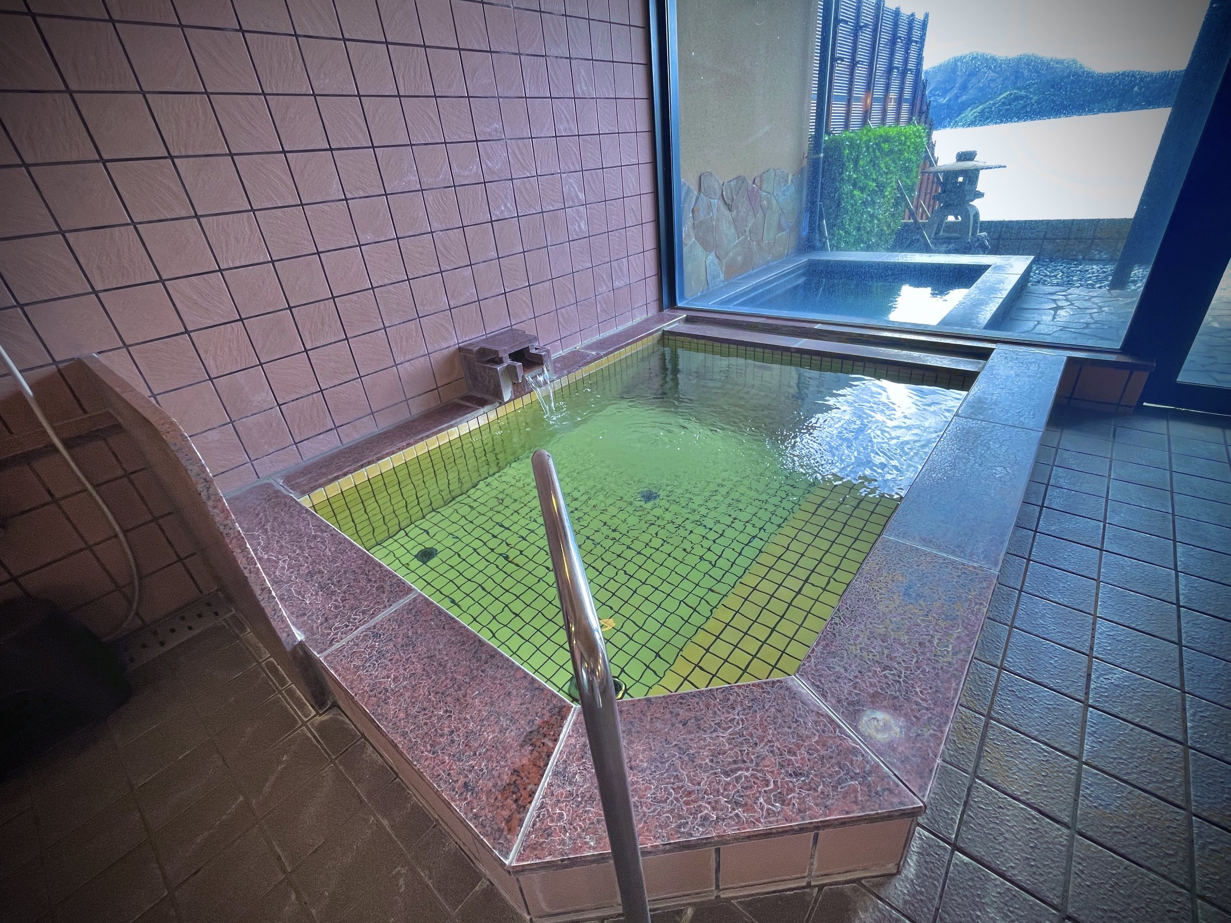 The indoor bath, with green tiles and a window on to the lake.