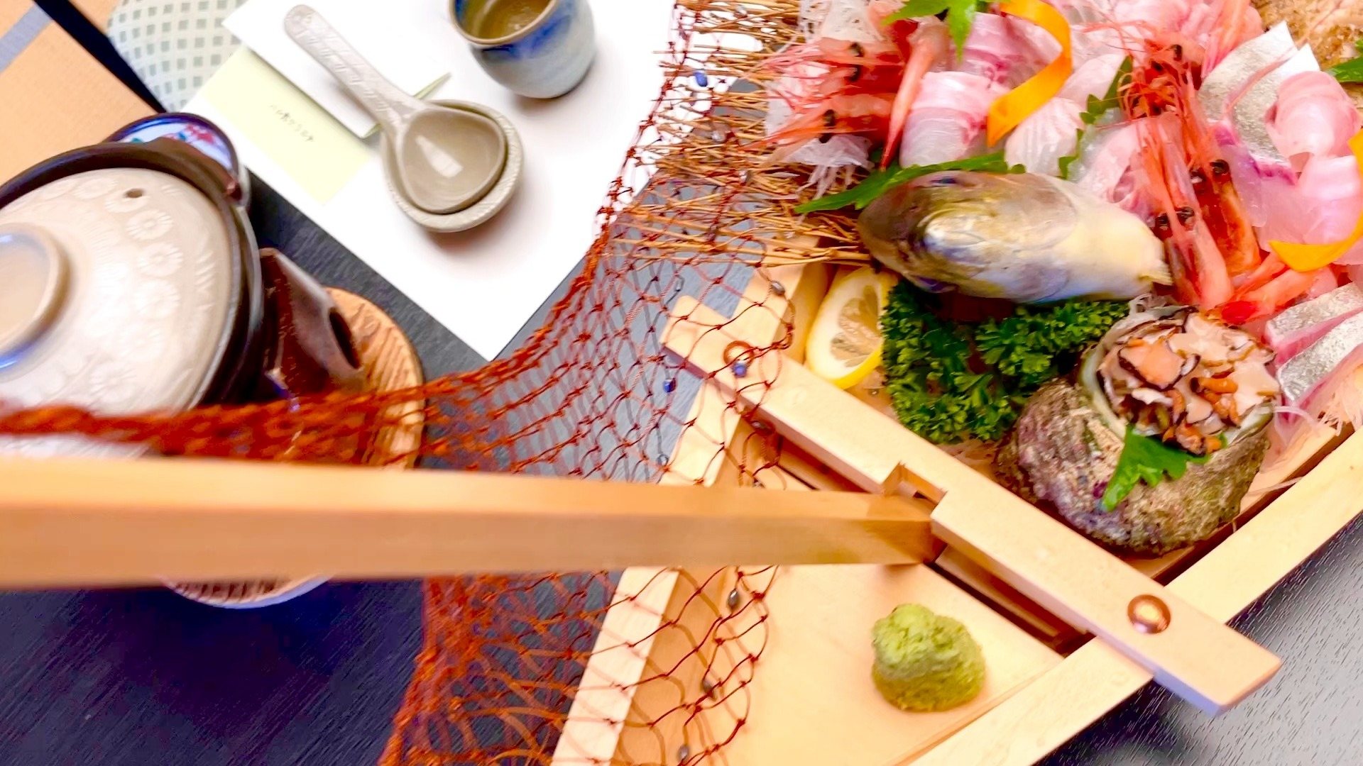 A boat-shaped platter of sashimi, with a fishing net draped over it.