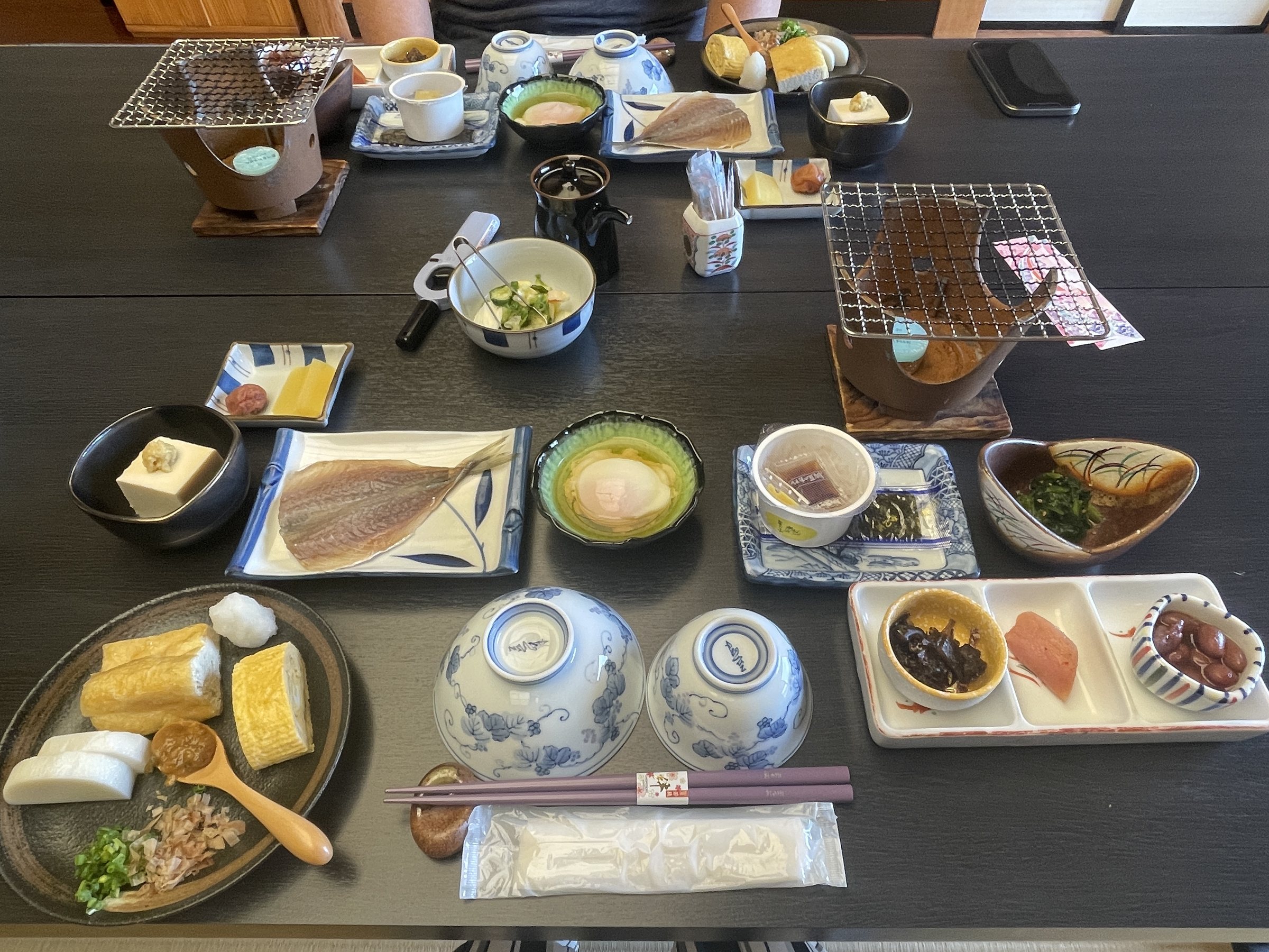 Breakfast laid out on the table, with dried fish on small grills.