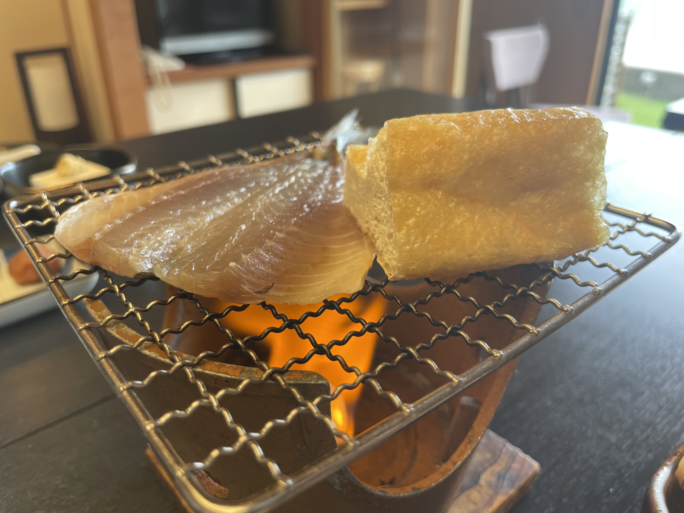 Dried fish and a thick slab of fried tofu over the flame.