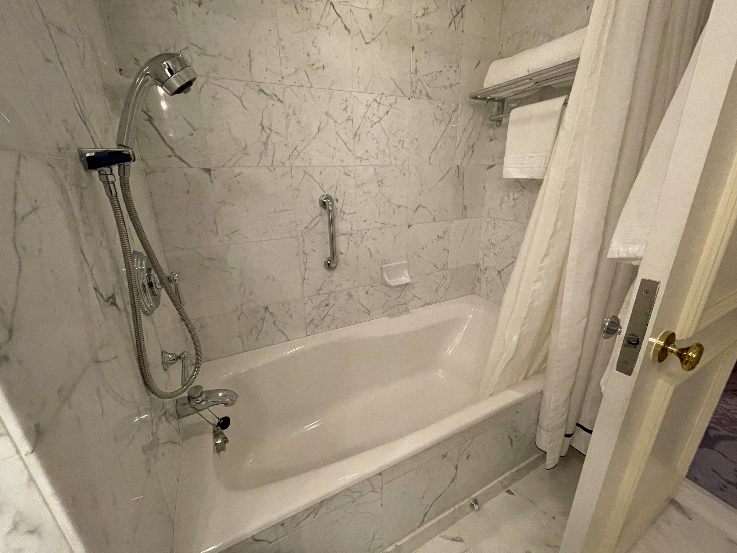 The marble-lined bathtub with a hand shower.