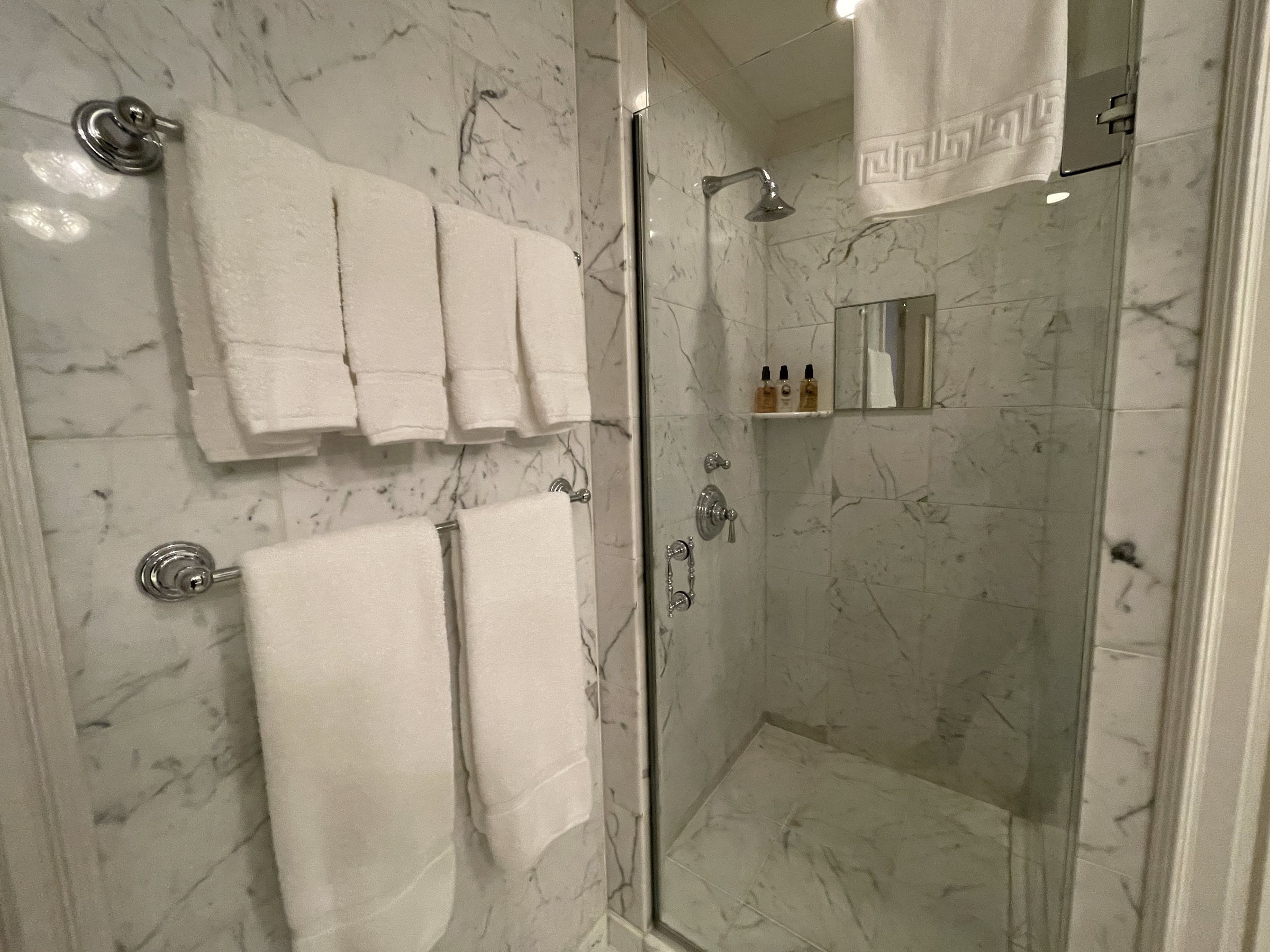 Stacks of white towels beside the glass-walled shower.