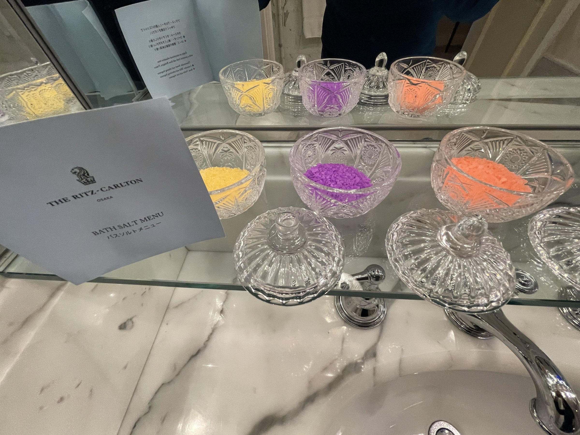 Colored bath salts in cut-glass bowls.