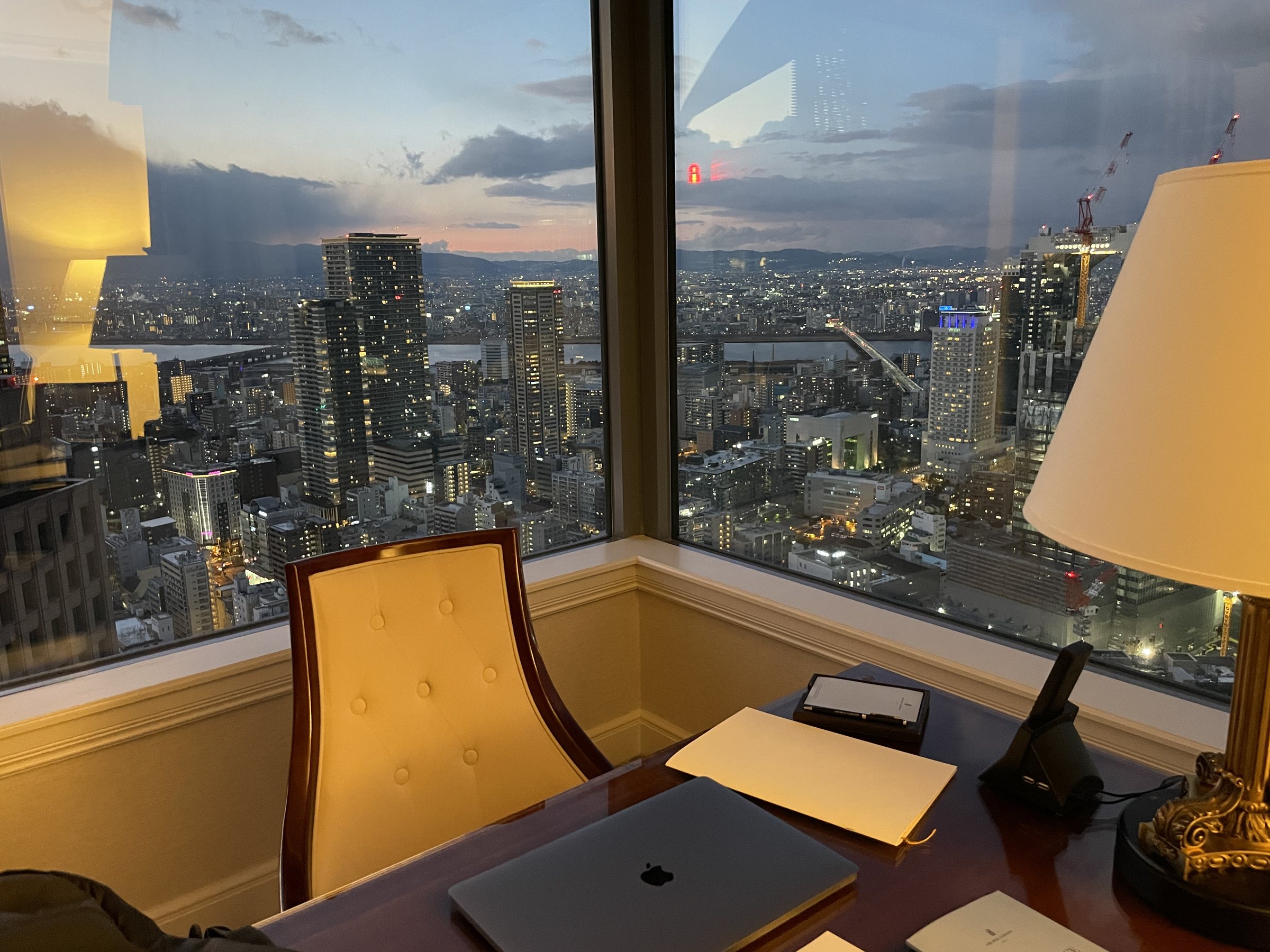 Osaka at dusk from the room, the city lights coming on below.