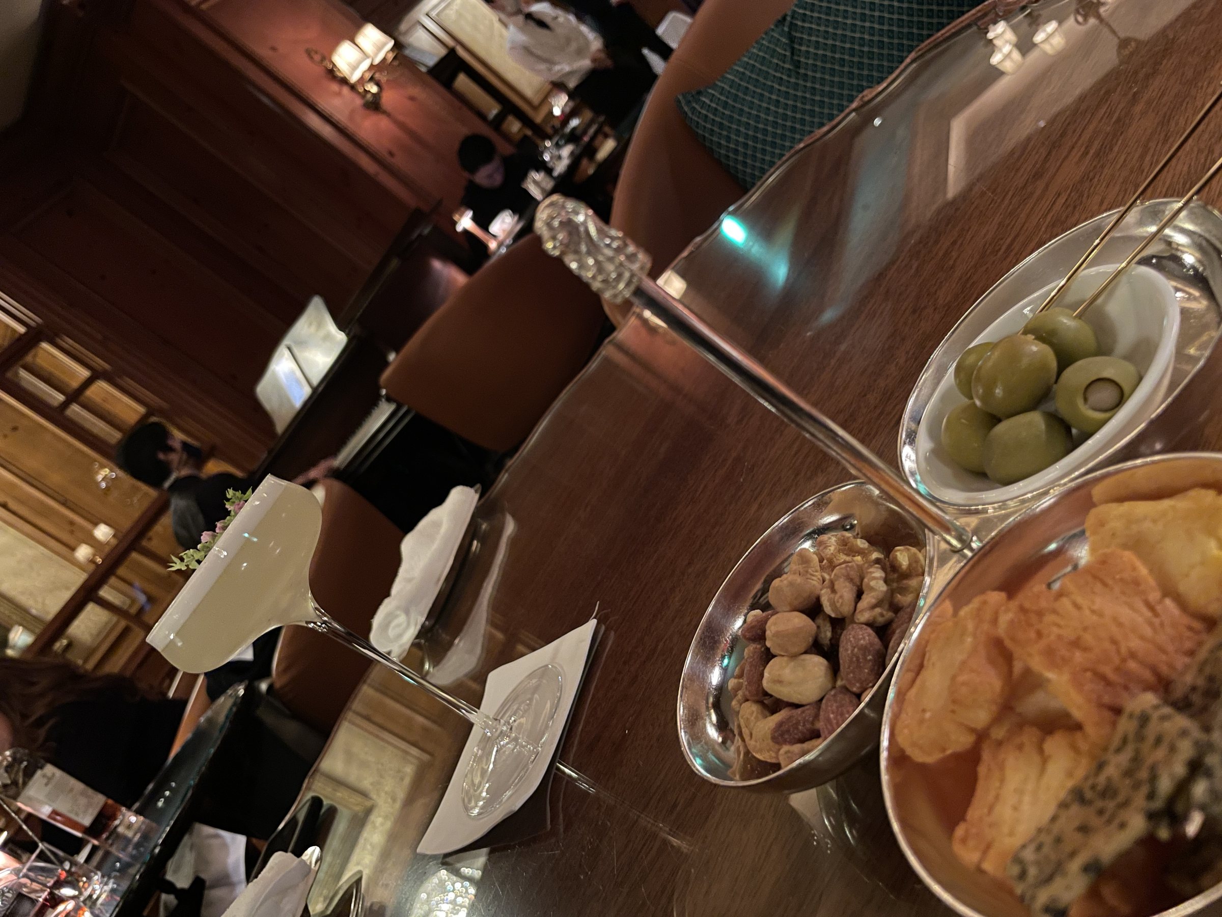 Olives, nuts and crisps on the bar table, photographed at a tilt.