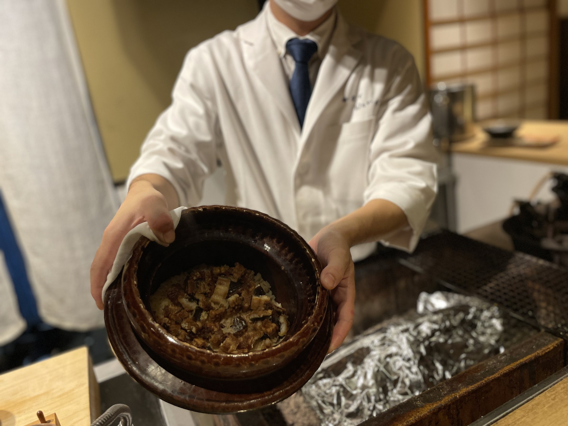 A cook presents the earthenware pot of rice cooked with conger eel.