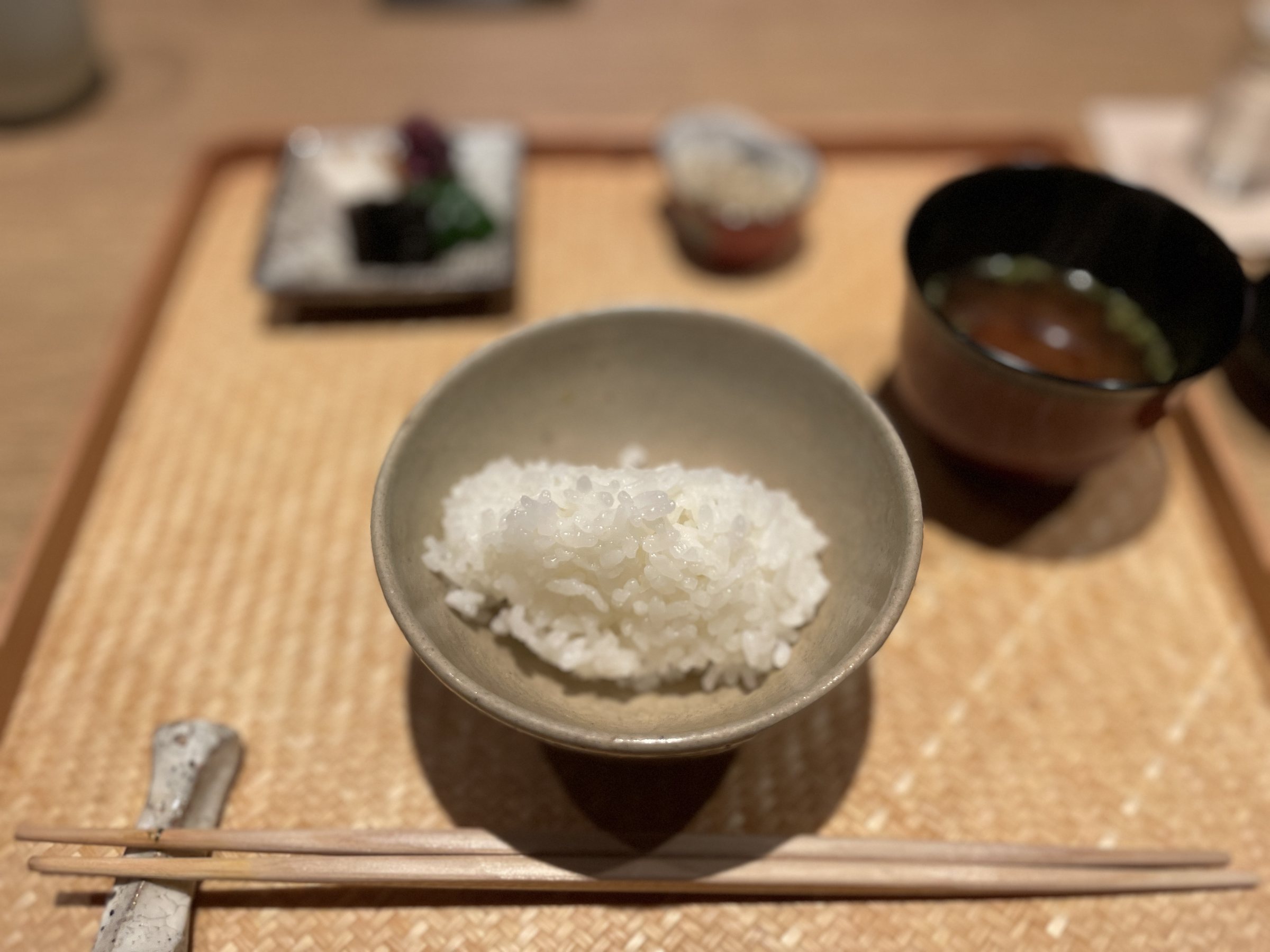 A bowl of white rice with miso soup and pickles.