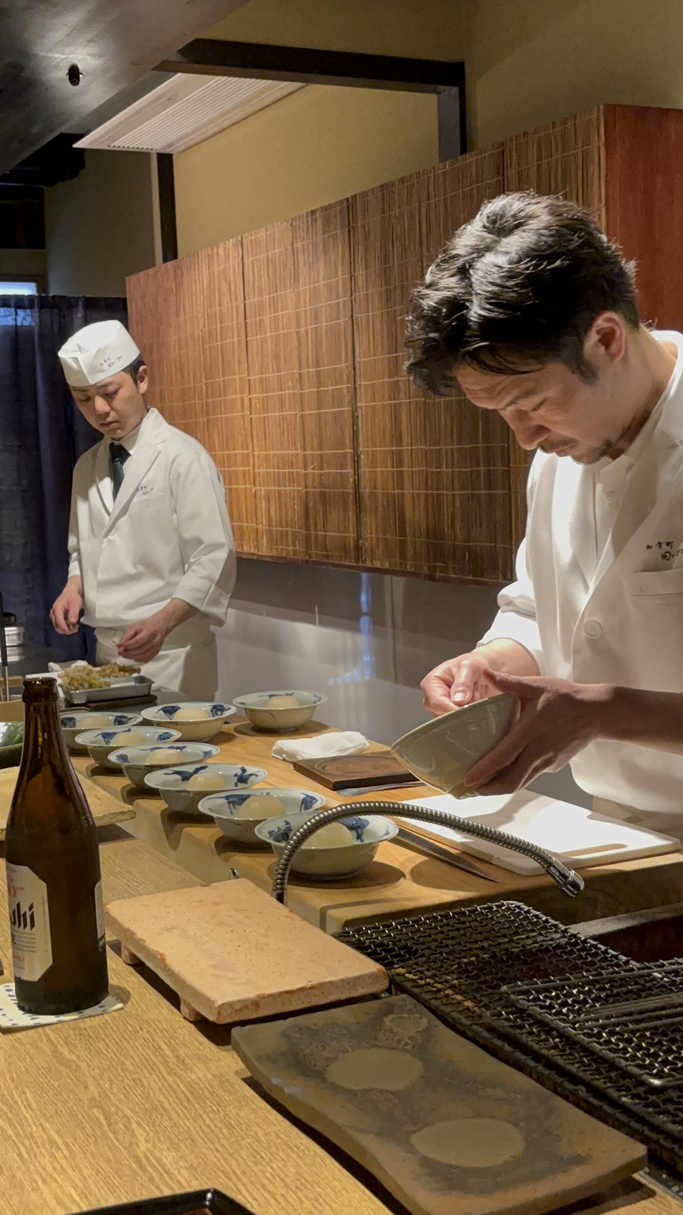 Two cooks preparing dishes beside the grill.