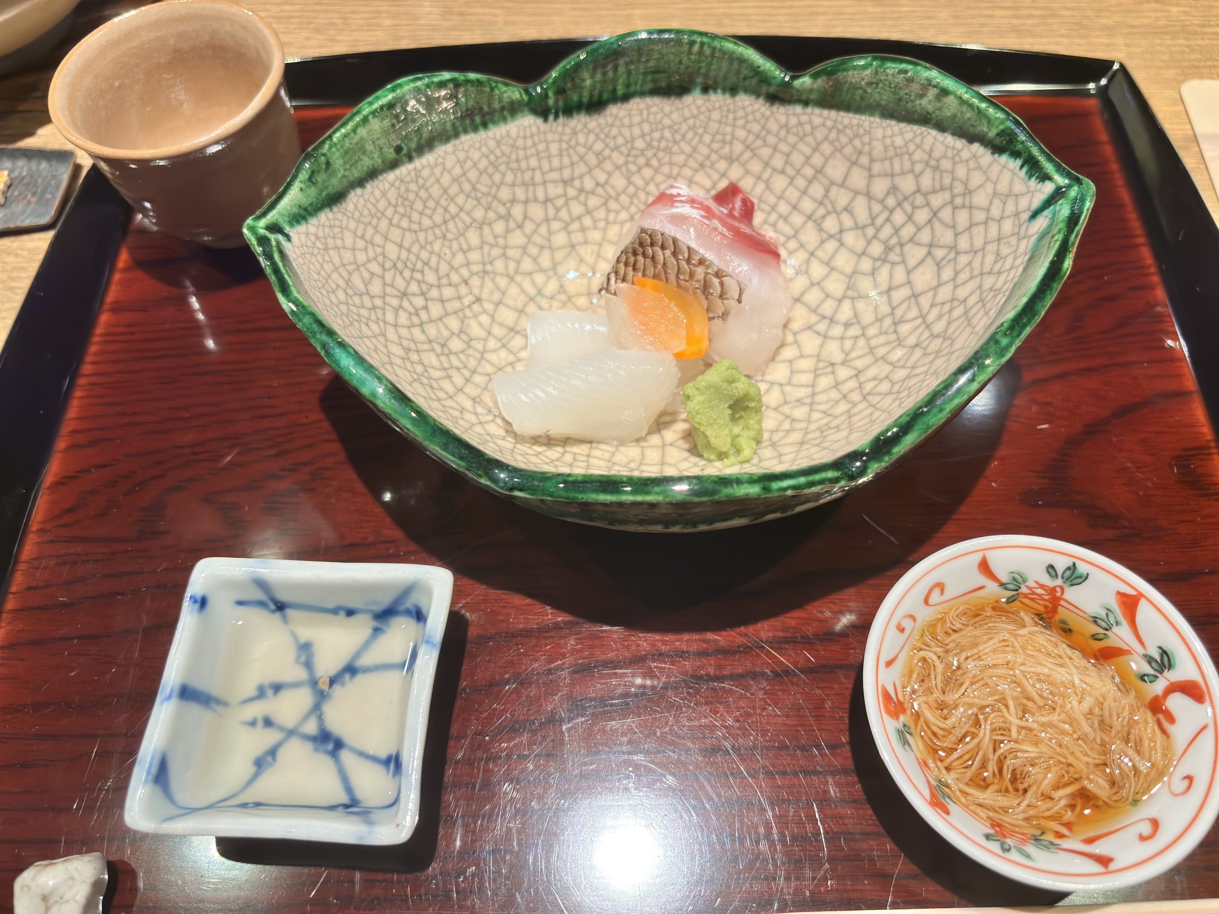 Sashimi on a leaf-shaped dish, with small dishes of condiments.