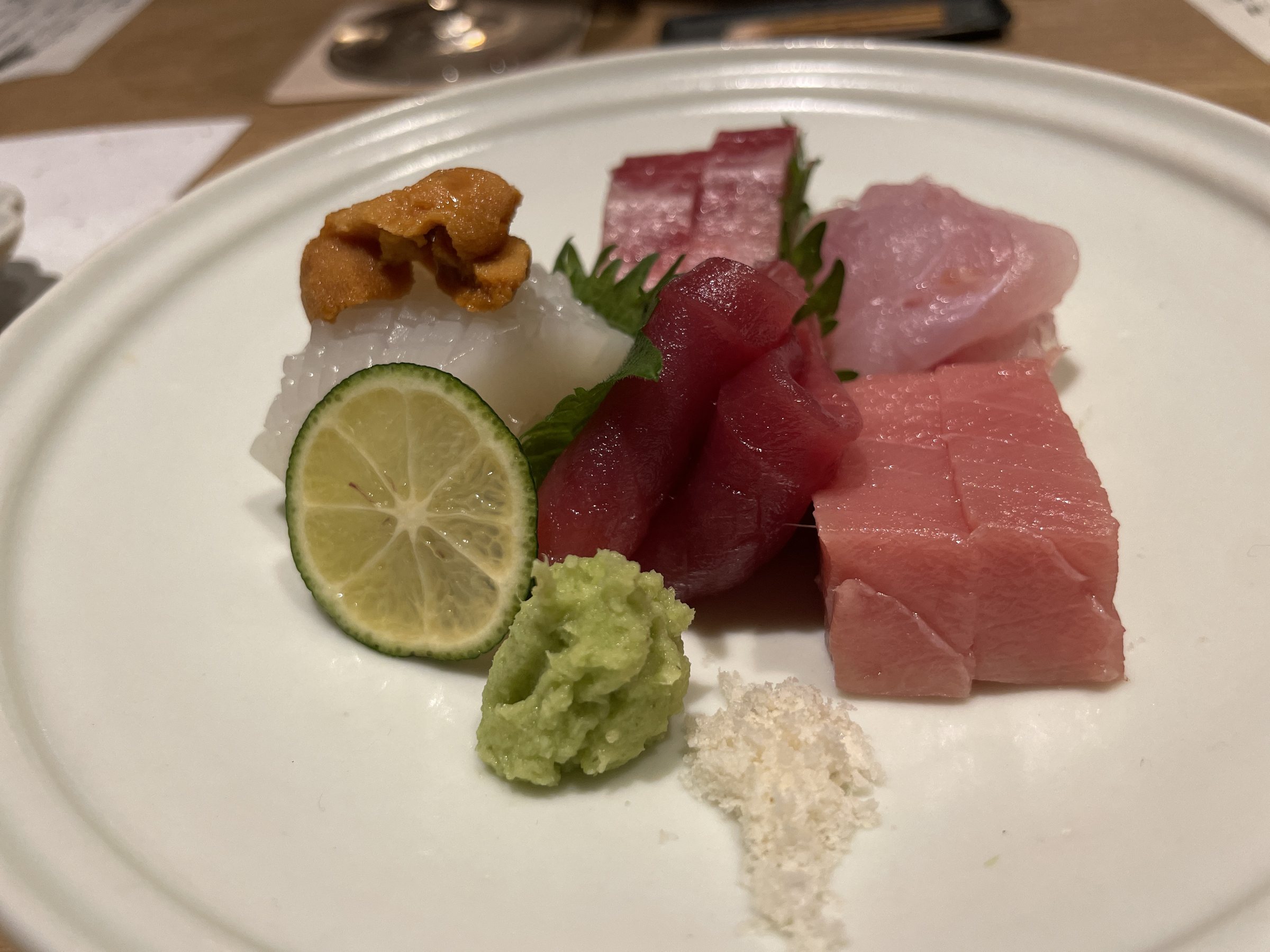 A sashimi platter of tuna, toro and other fish, with sea urchin, sudachi and wasabi.