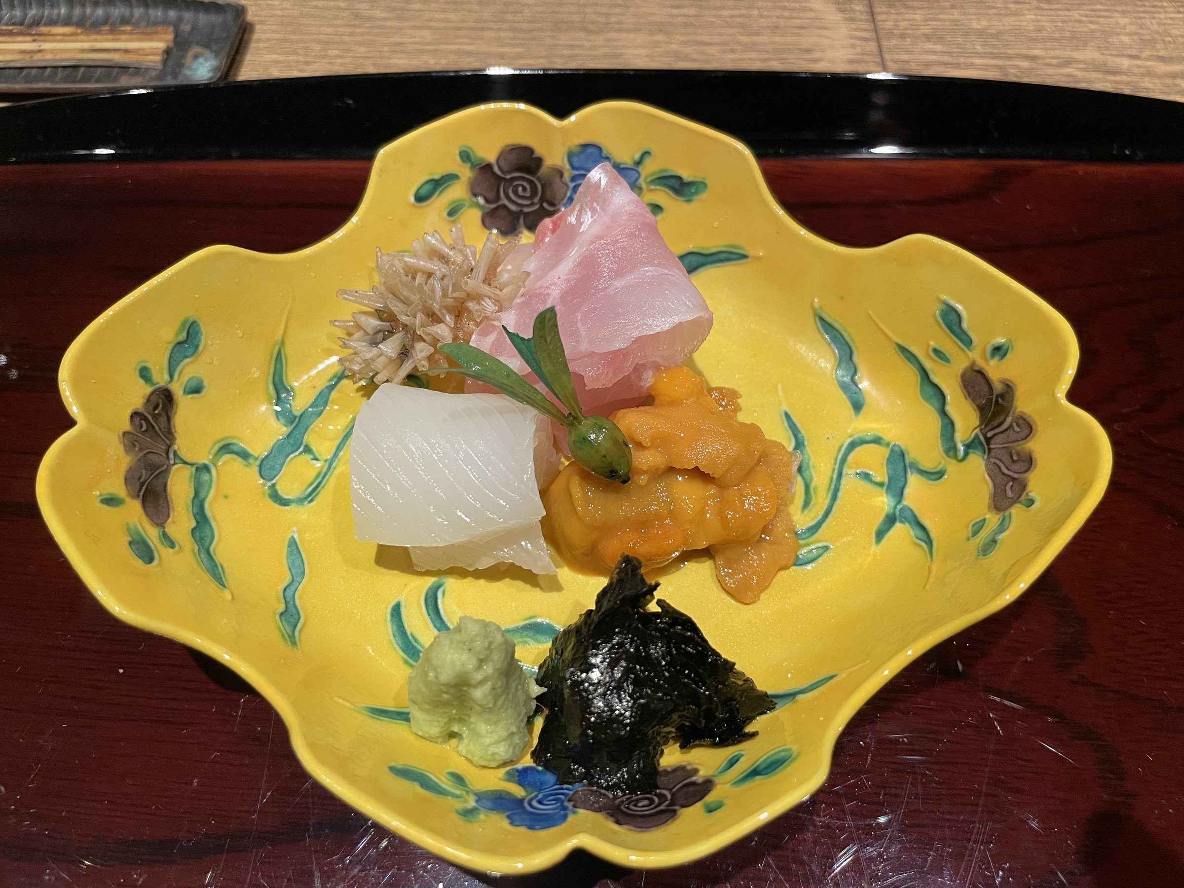 Sashimi in a yellow patterned dish: squid, sea urchin and white fish, with wasabi and nori tsukudani.