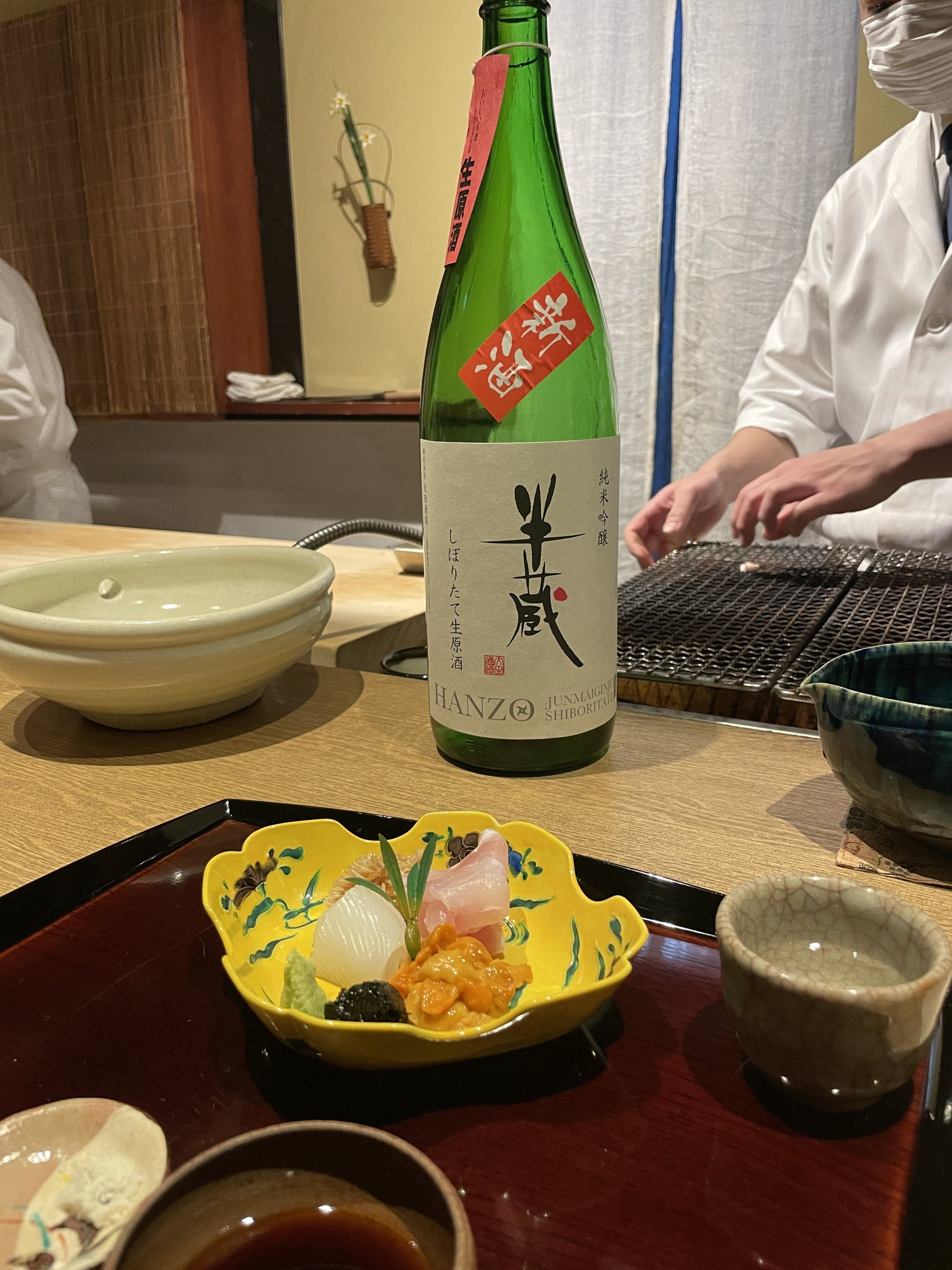 A bottle of sake on the counter beside the sashimi.