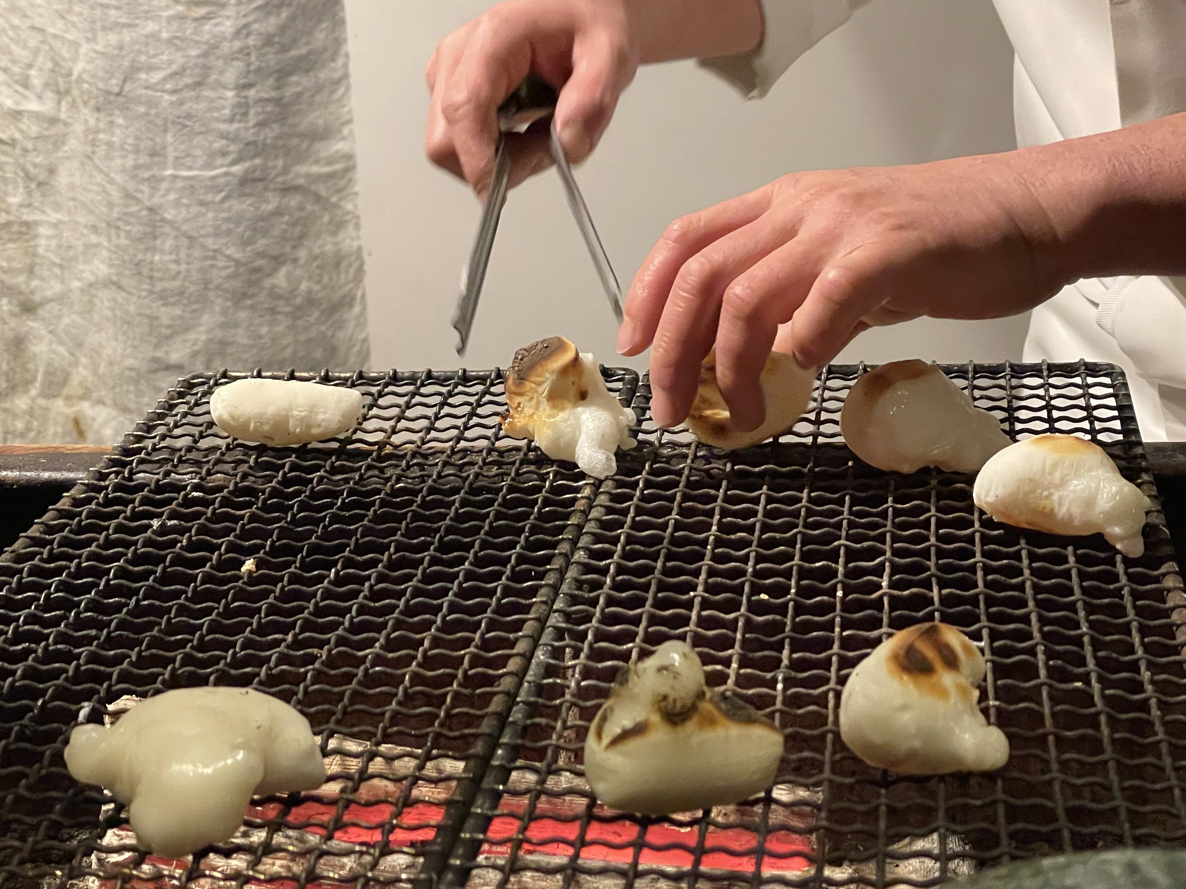 Small rice cakes toasting on the grill over the hearth.