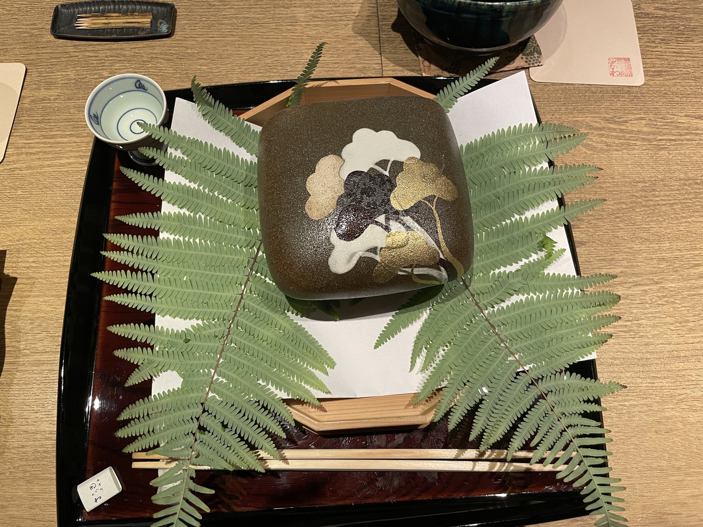 A small patterned dish set on fern fronds.
