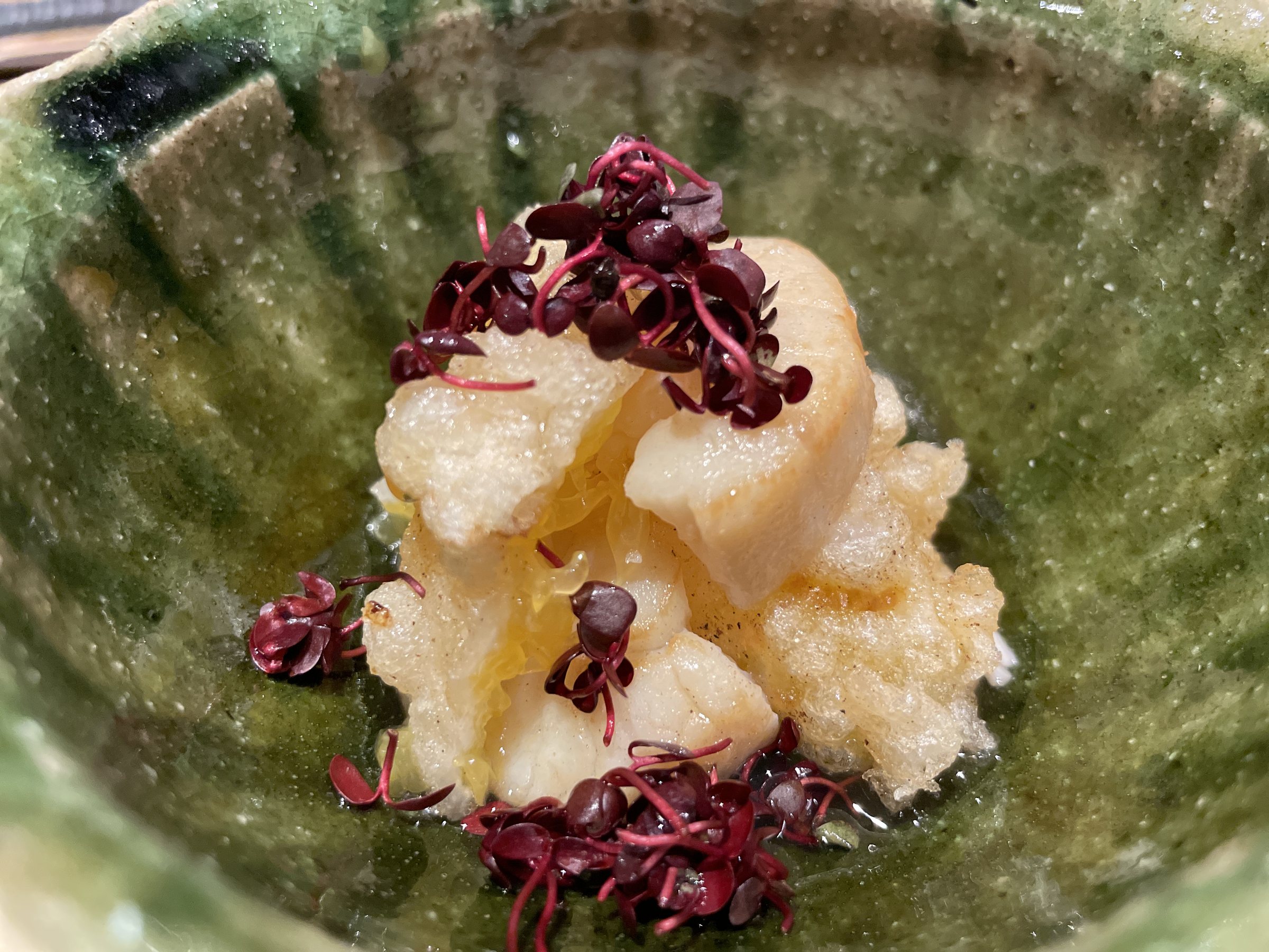 Scallop tempura with citrus and purple sprouts in a green-glazed bowl.