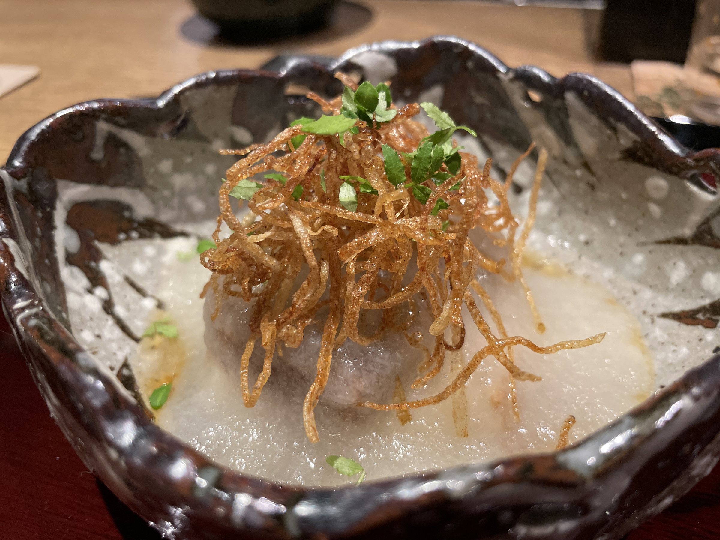 A dish topped with grated daikon and a tangle of crisp fried shreds.