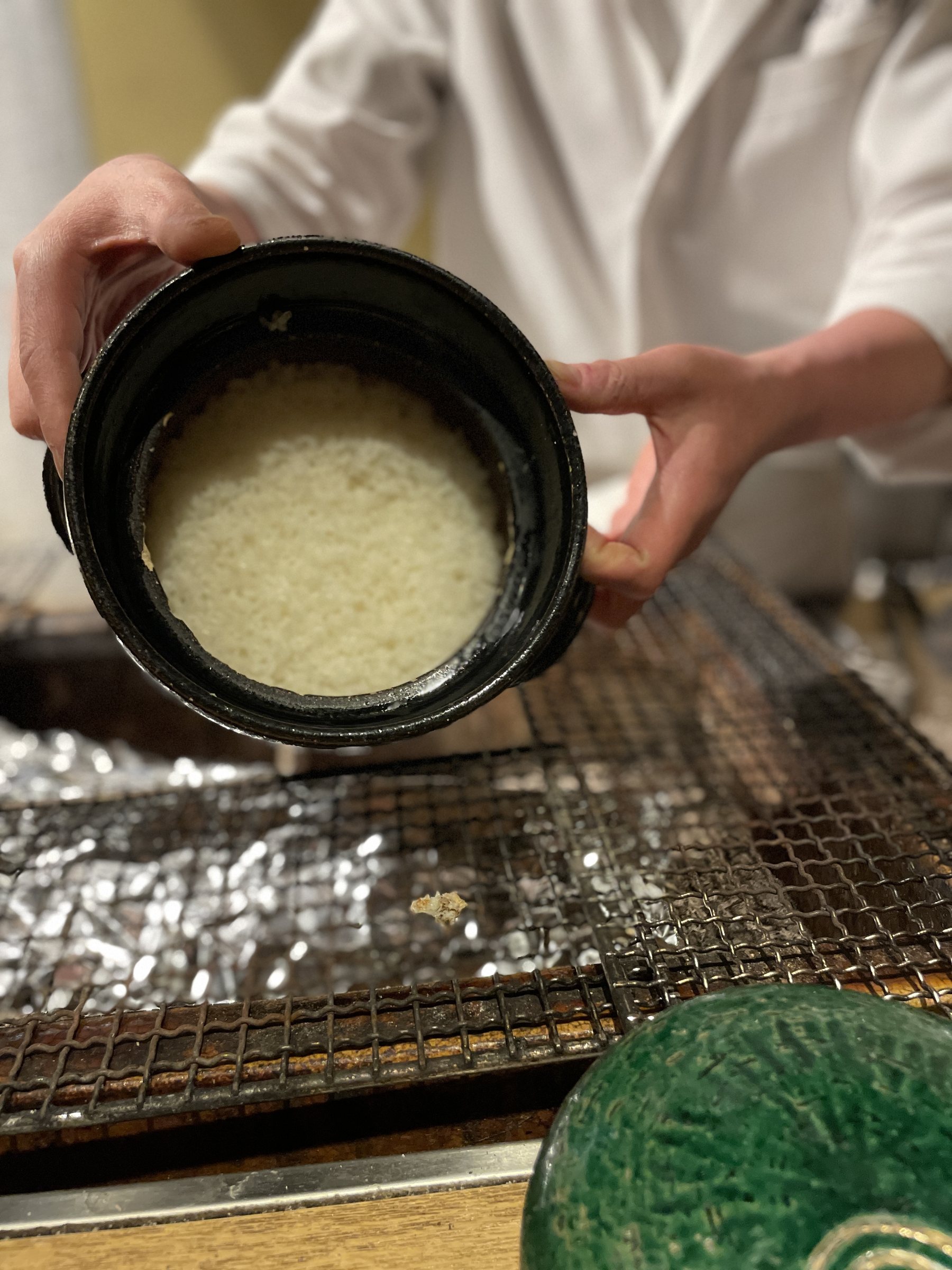 A cook presents an earthenware pot of rice.