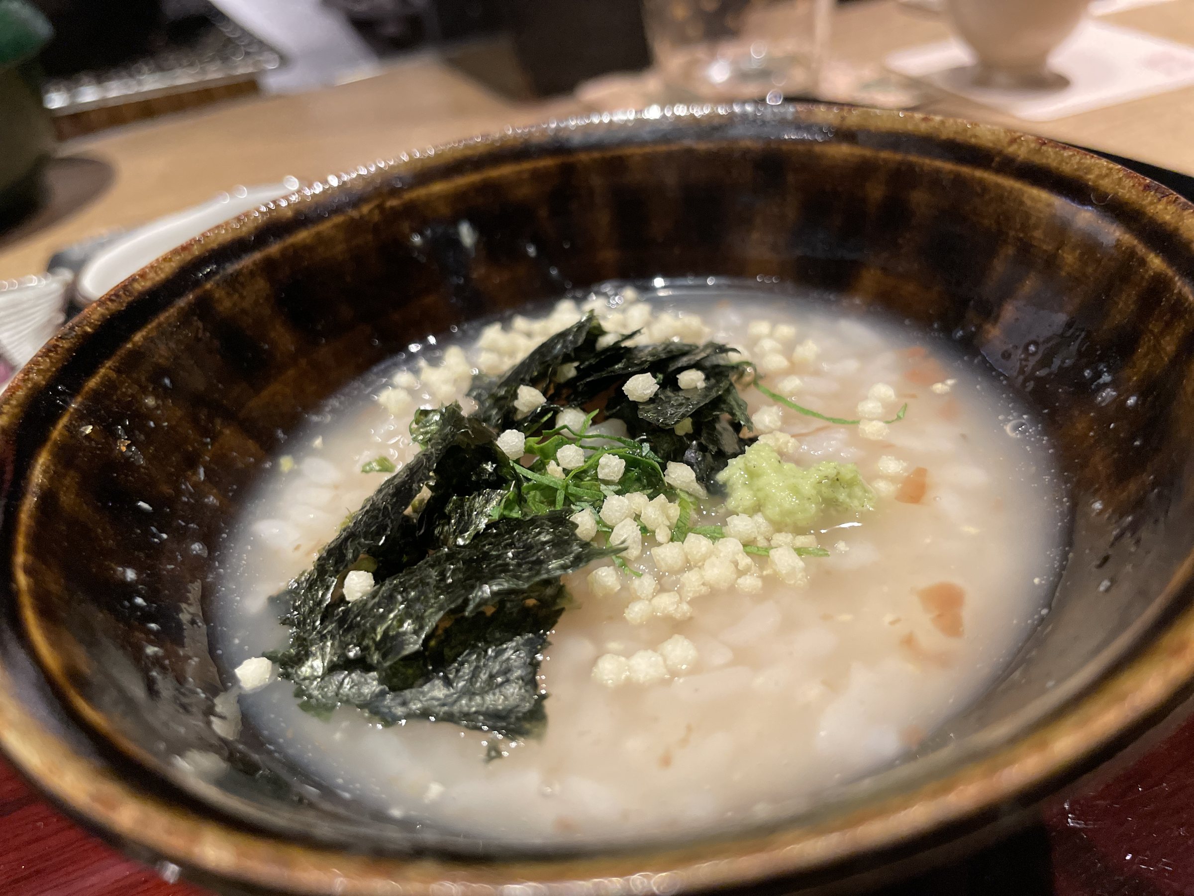 Plum porridge topped with nori, rice crackers and shiso.