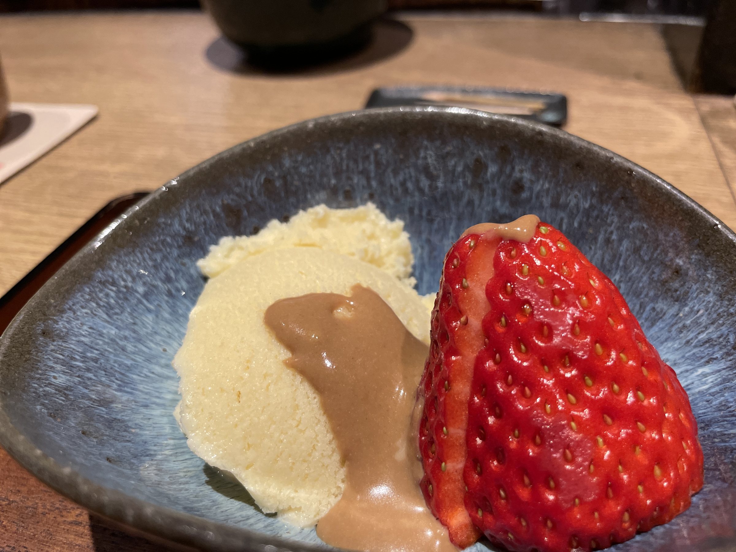 White sesame ice with a creamy sauce and a halved strawberry.