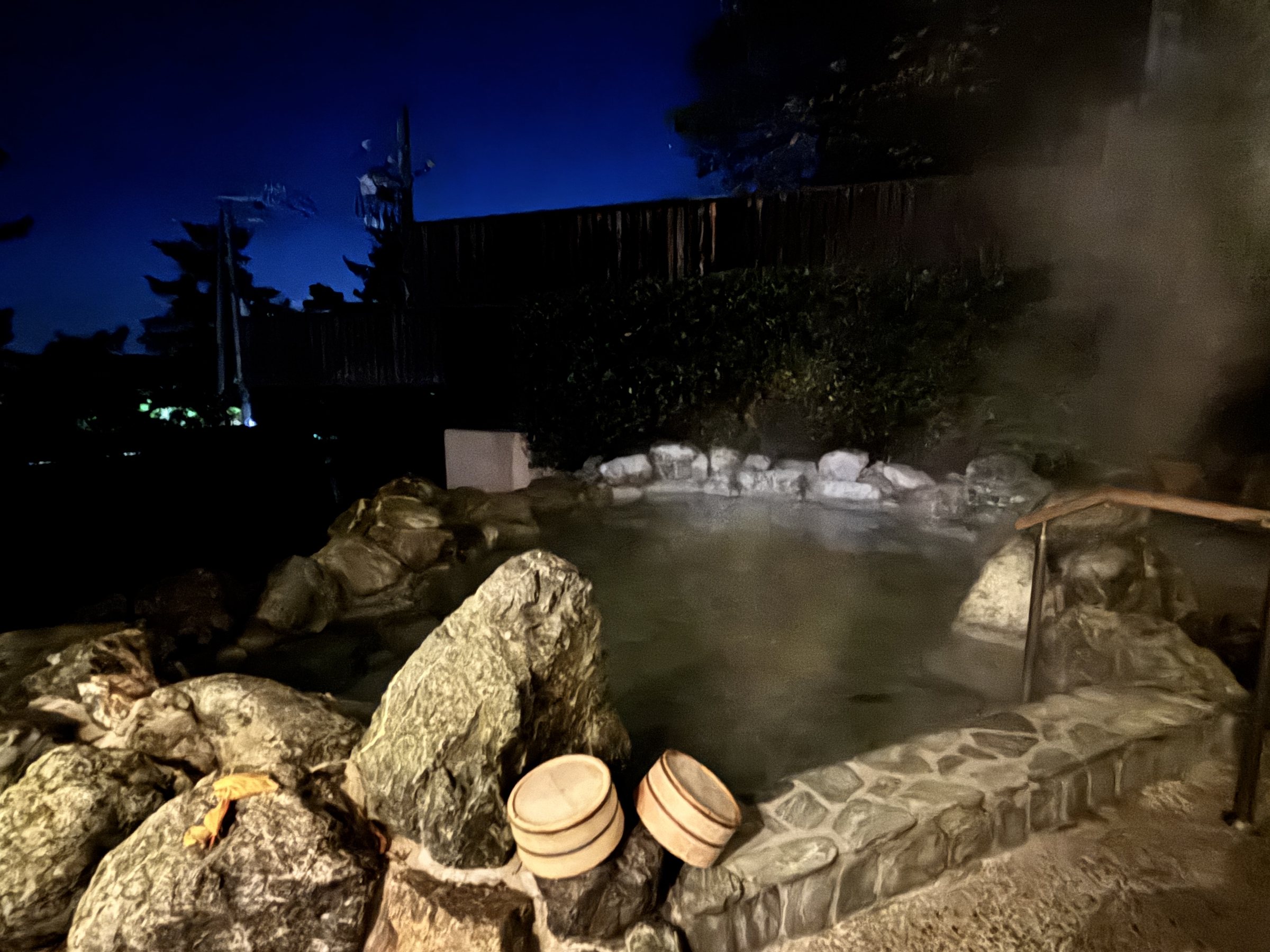 The rock-built open-air bath, steaming in the dark.