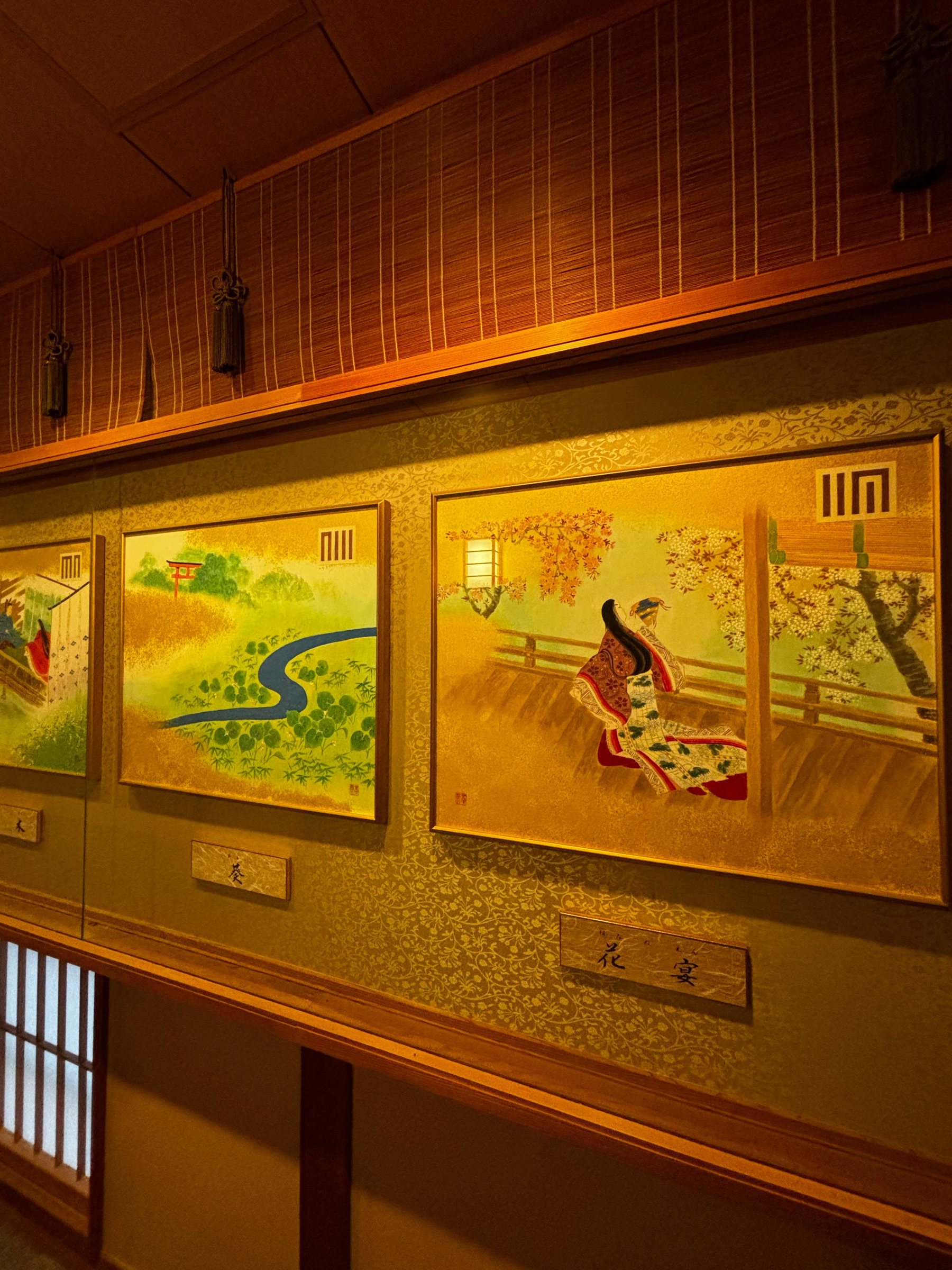 Gold-ground paintings from The Tale of Genji, displayed under glass along the corridor.