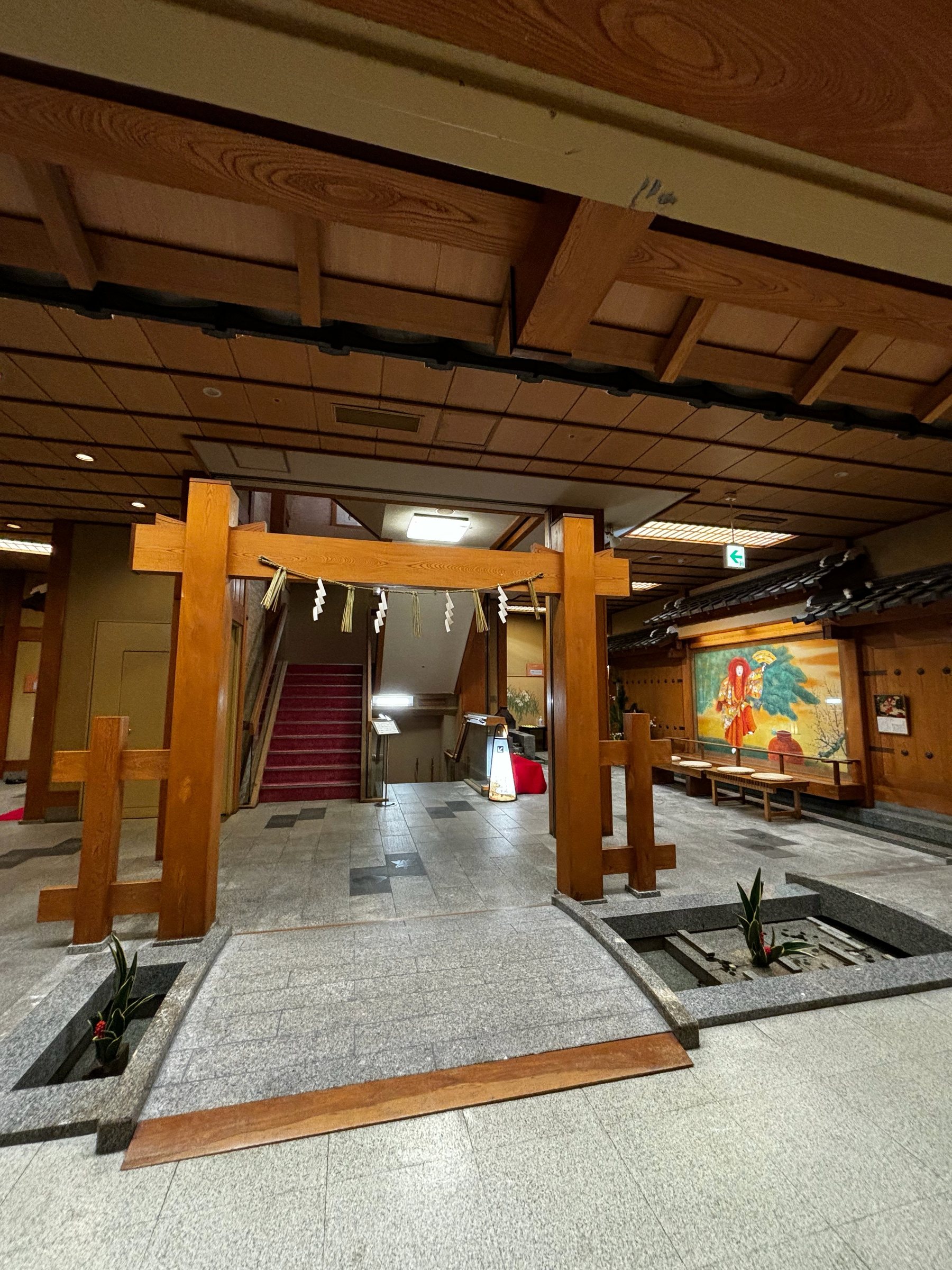 A wooden torii hung with a sacred rope, standing indoors in the lobby.
