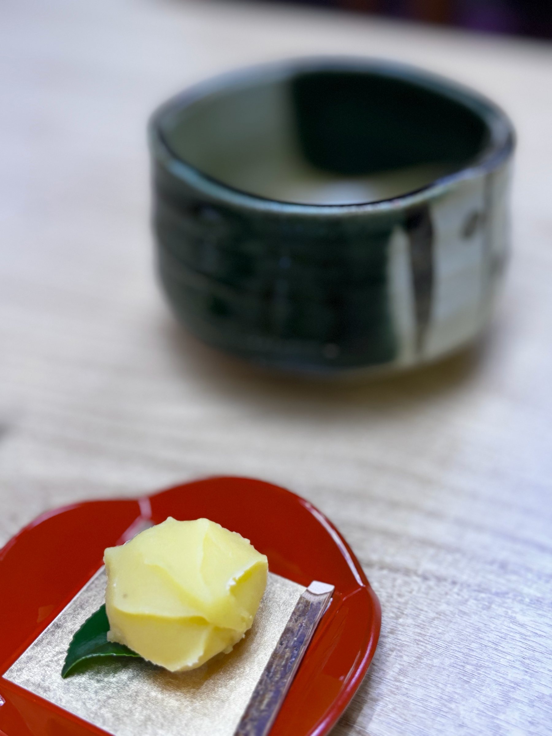 A bowl of matcha and a pale sweet on a red lacquer dish.