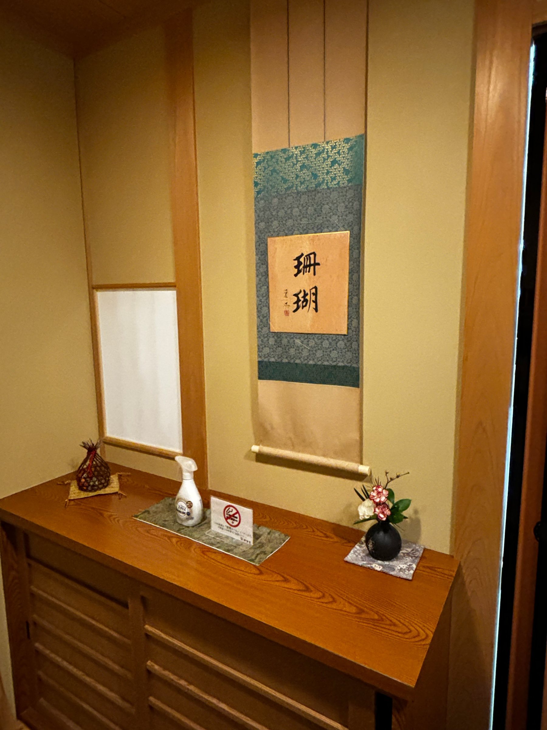The alcove of the tatami room, with a hanging scroll and a small flower arrangement.