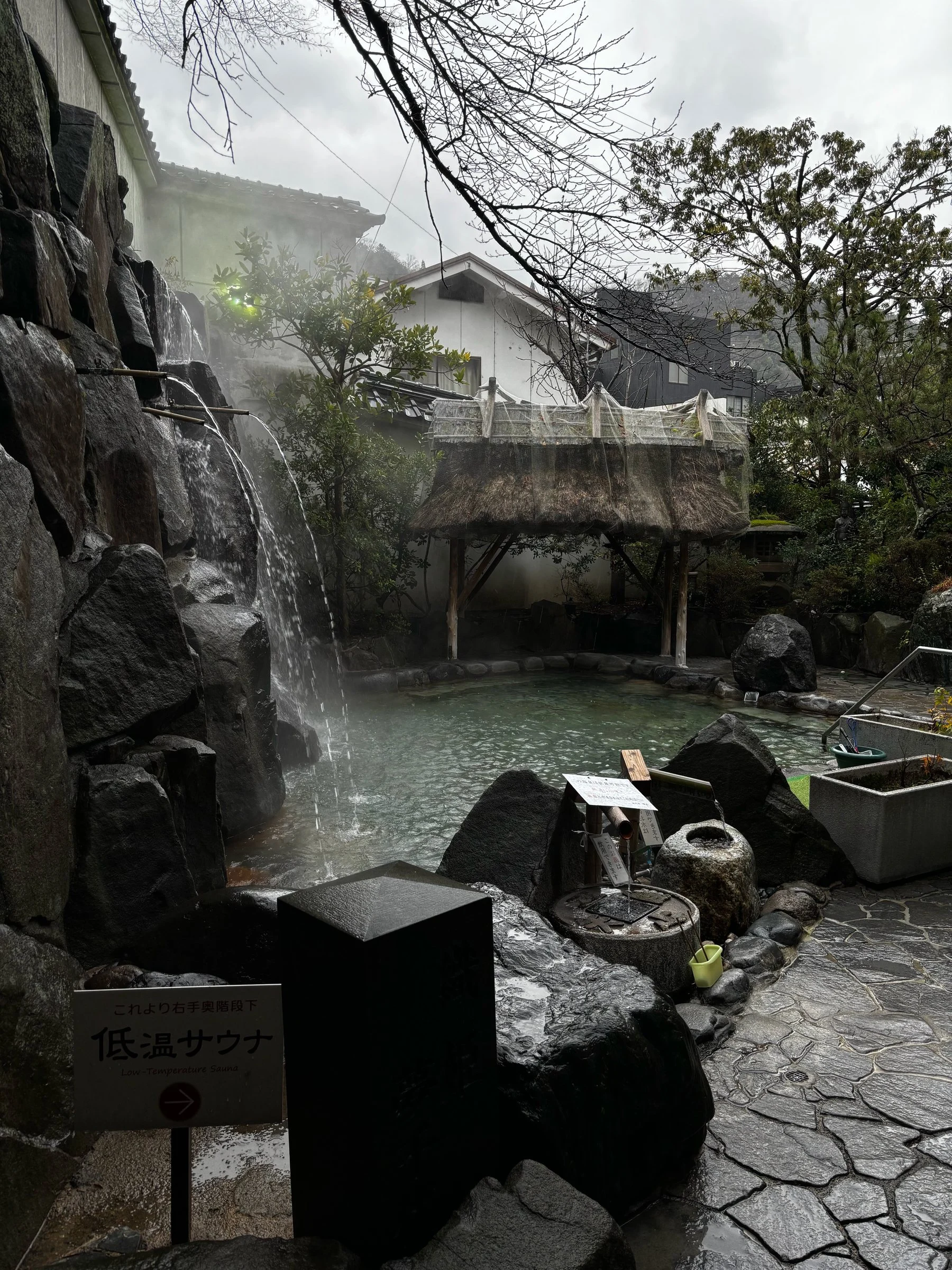 The outdoor bath, with its rock waterfall and steam rising into the trees.