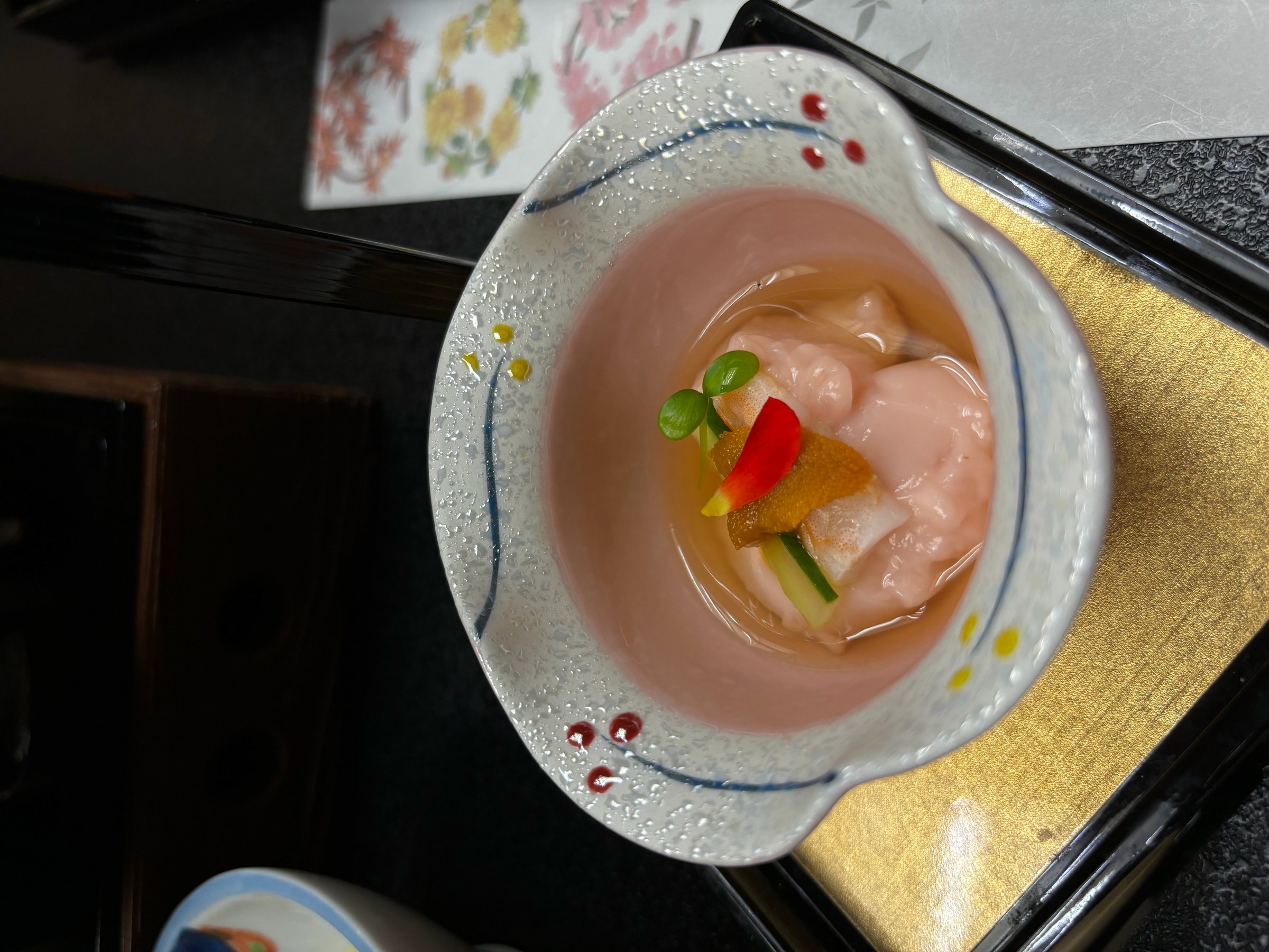 Clams in dashi jelly, with sea urchin and sprouts, in a pink bowl.
