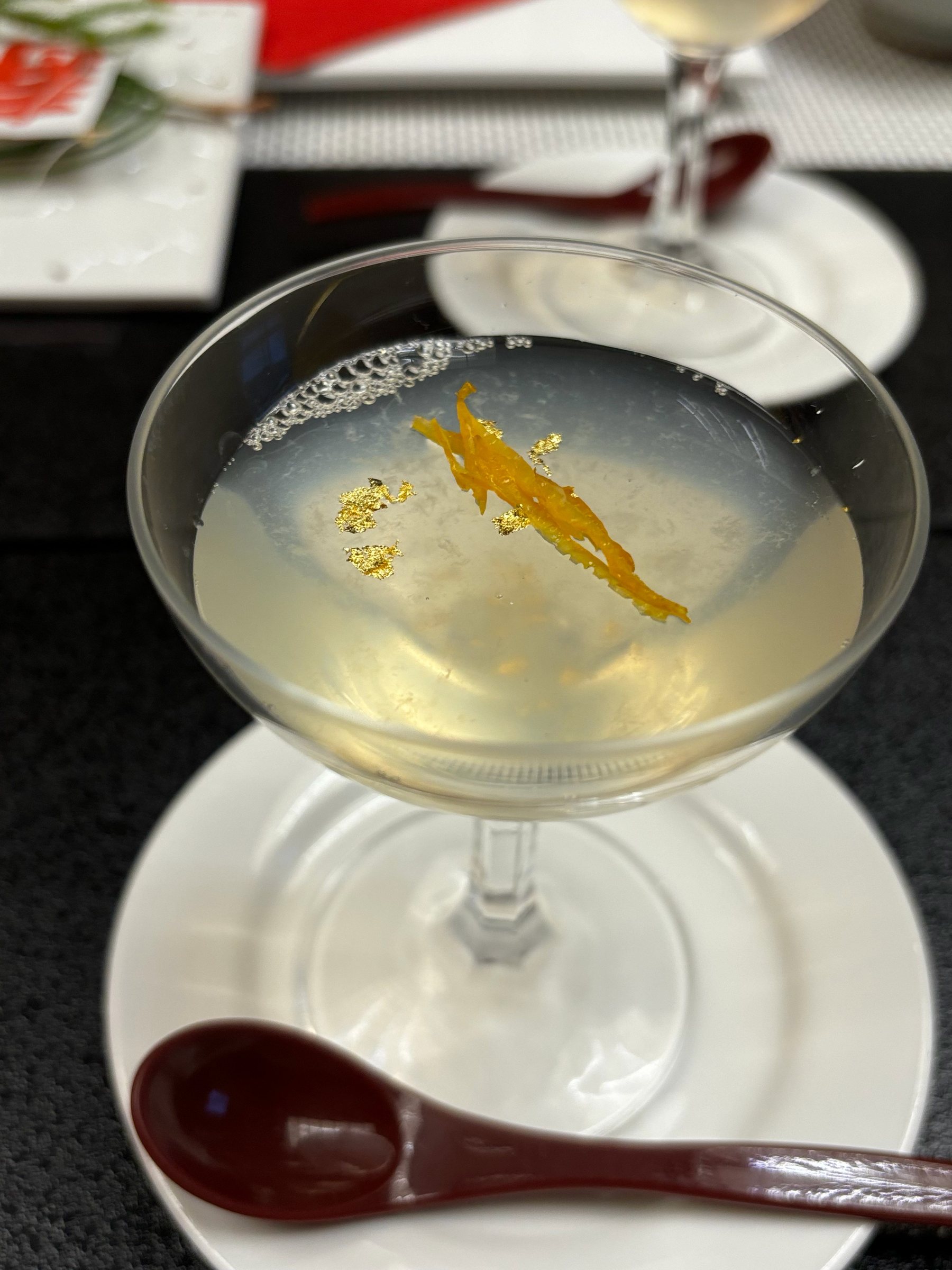 A house-made jelly in a cocktail glass, with gold leaf and citrus peel.